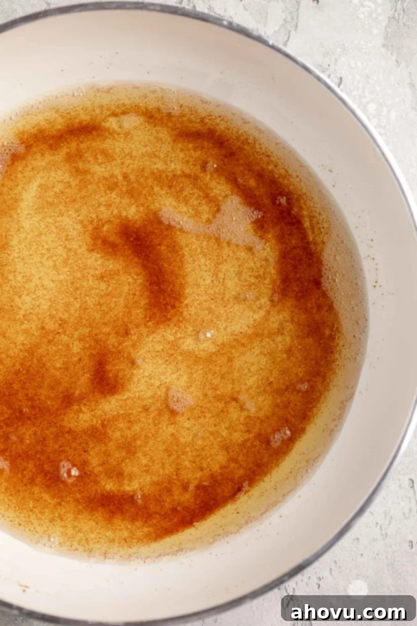 The Art of Brown Butter 9 A closeup view of rich brown butter in a white skillet, highlighting the texture of the toasted milk solids.