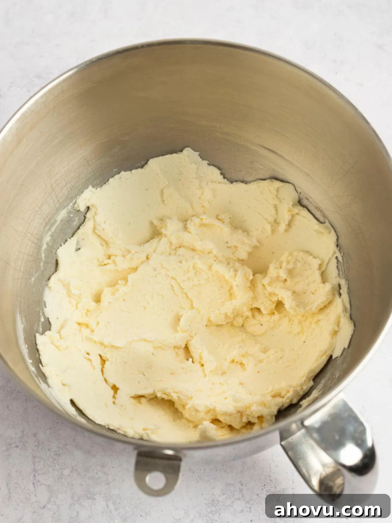 Butter and powdered sugar partially mixed together in the bowl of a stand mixer, showing the frosting beginning to form.