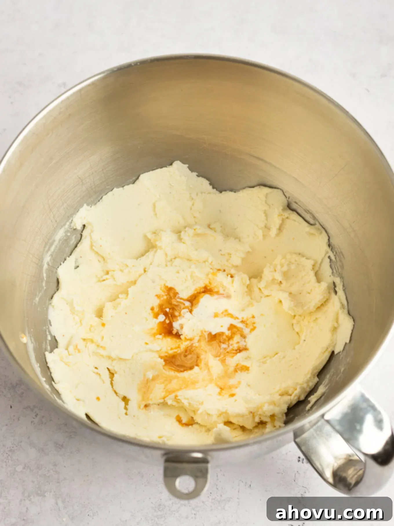 Heavy cream, pure vanilla extract, and a pinch of salt freshly added on top of the creamed butter and powdered sugar mixture.