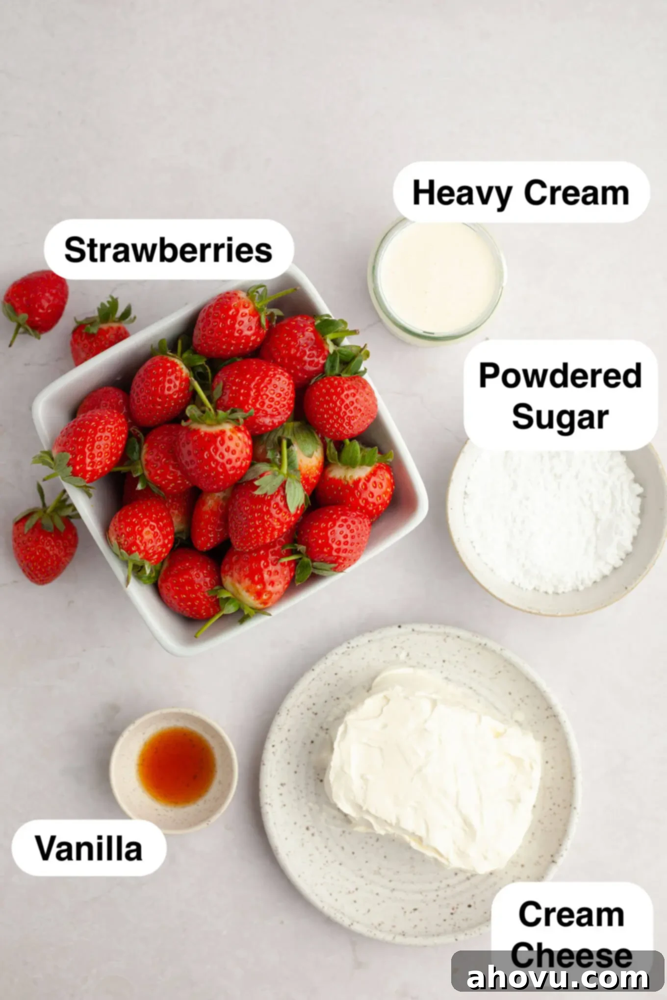 Strawberry Cheesecake Poppers 3 An overhead view of the essential ingredients laid out to make no-bake cheesecake stuffed strawberries: fresh strawberries, cream cheese, powdered sugar, heavy cream, and vanilla extract.