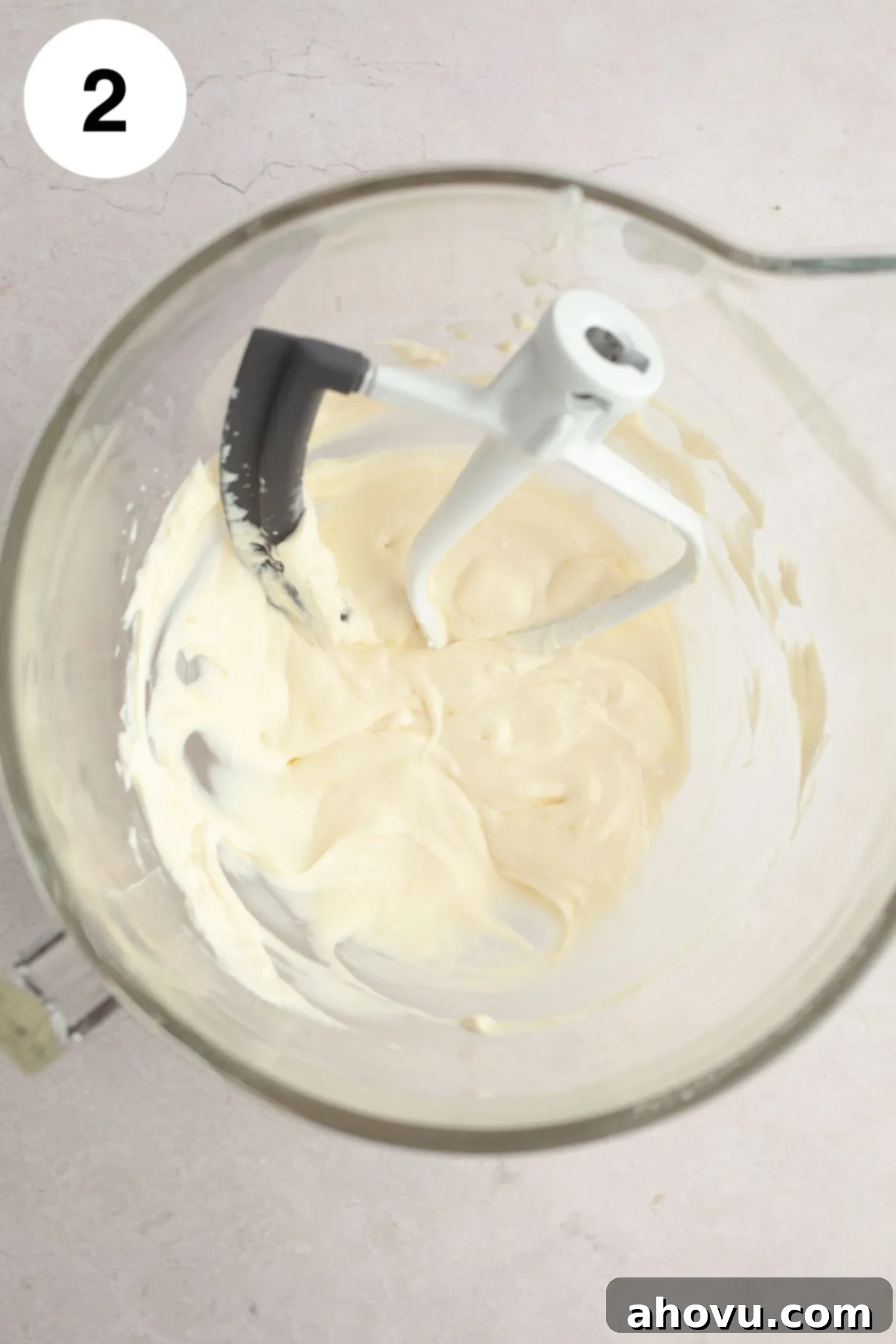 Strawberry Cheesecake Poppers 5 An overhead view of softened cream cheese being beaten until perfectly smooth in a stand mixer with a paddle attachment.