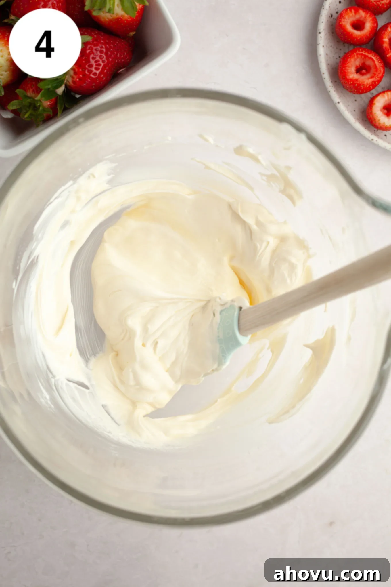 Strawberry Cheesecake Poppers 7 An overhead view of the completed cheesecake filling mixture in a glass bowl, ready for piping, with a rubber spatula.