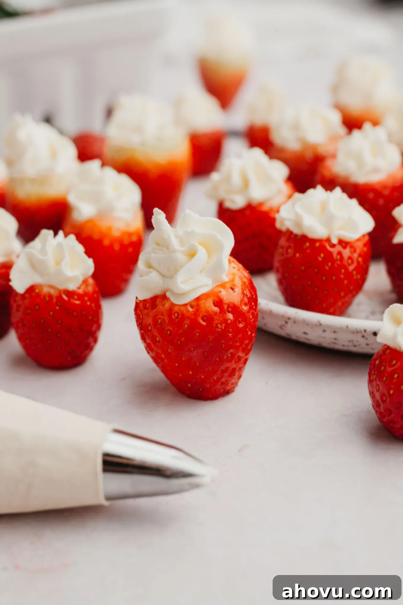 Strawberry Cheesecake Poppers 9 A stunning arrangement of cheesecake stuffed strawberries standing upright, showcasing their beautiful piped filling, with a piping bag in the foreground.
