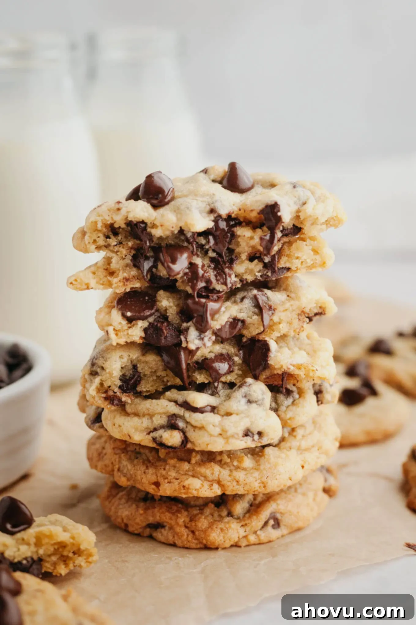 A stack of gooey cream cheese chocolate chip cookies on parchment paper, showcasing their soft texture and melted chocolate chips.