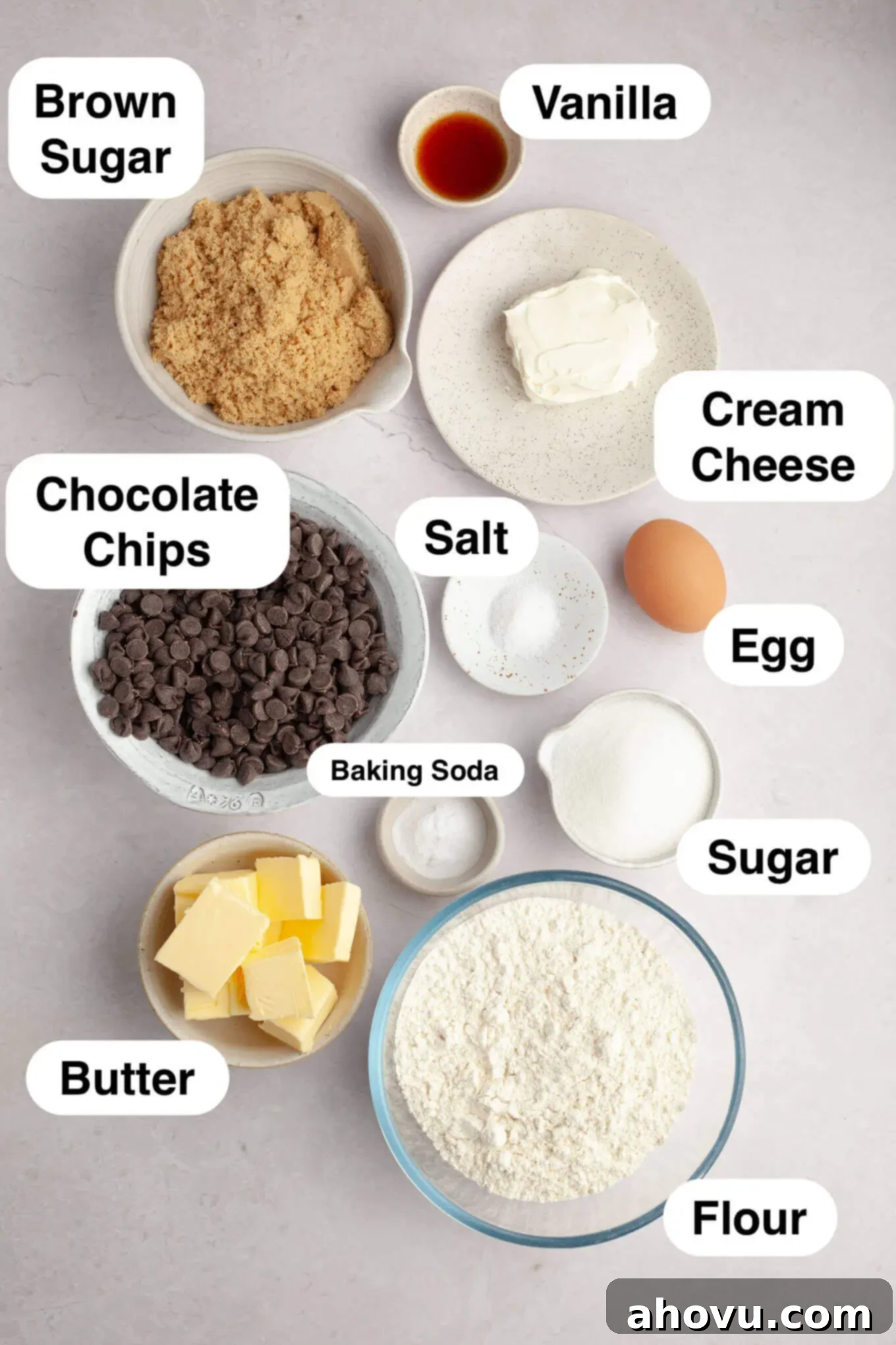 An overhead view of all the fresh ingredients carefully laid out for making cream cheese chocolate chip cookies, including butter, cream cheese, sugars, flour, and chocolate chips.