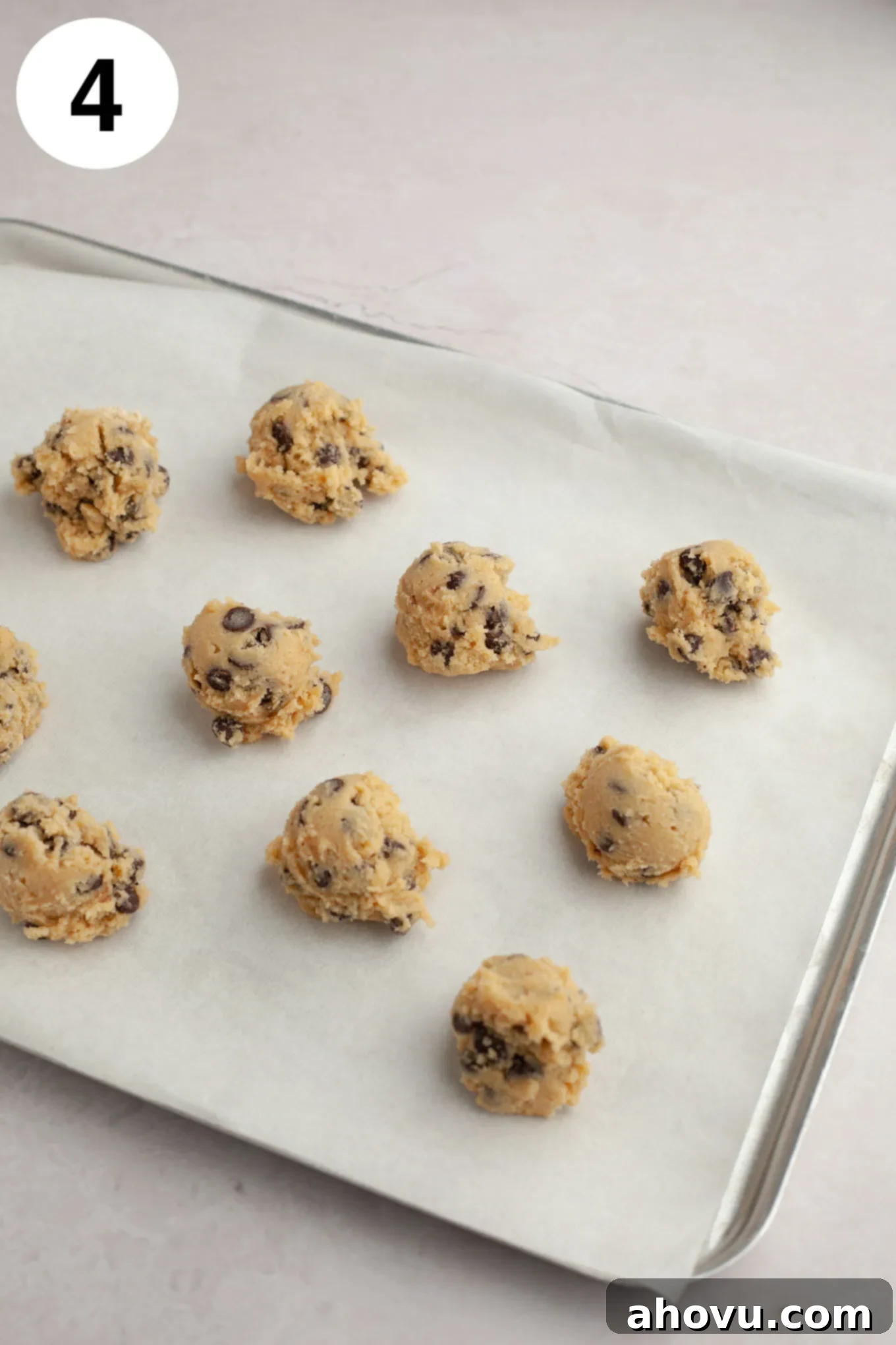 Perfectly scooped balls of cream cheese chocolate chip cookie dough arranged on a parchment paper-lined baking sheet, ready for chilling and baking.