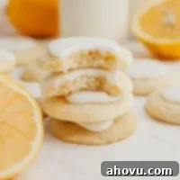 A stack of three lemon meltaway cookies topped with lemon icing. The top cookie is broken in half, showing its tender interior.