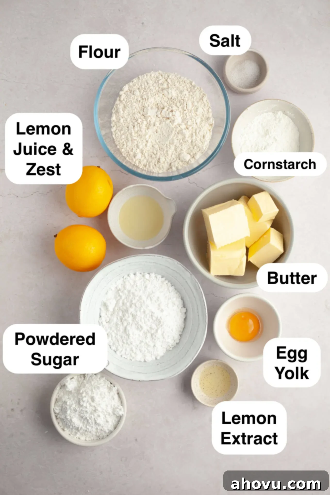 An overhead view of the fresh ingredients, including lemons, butter, and flour, laid out for making lemon meltaway cookies.