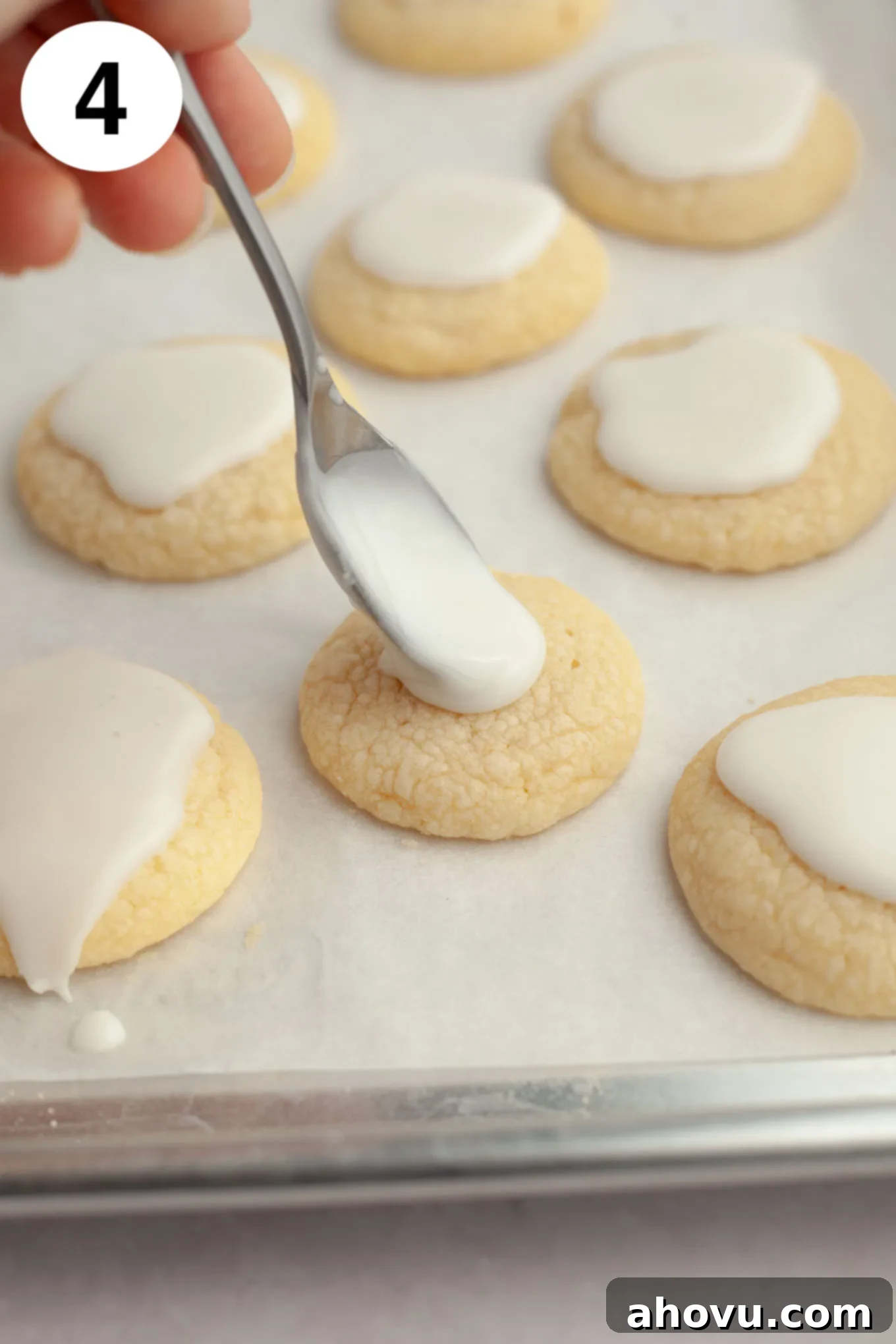 A process shot showing a stream of glossy lemon icing being artfully drizzled over a batch of freshly baked, soft lemon cookies, adding the final touch.
