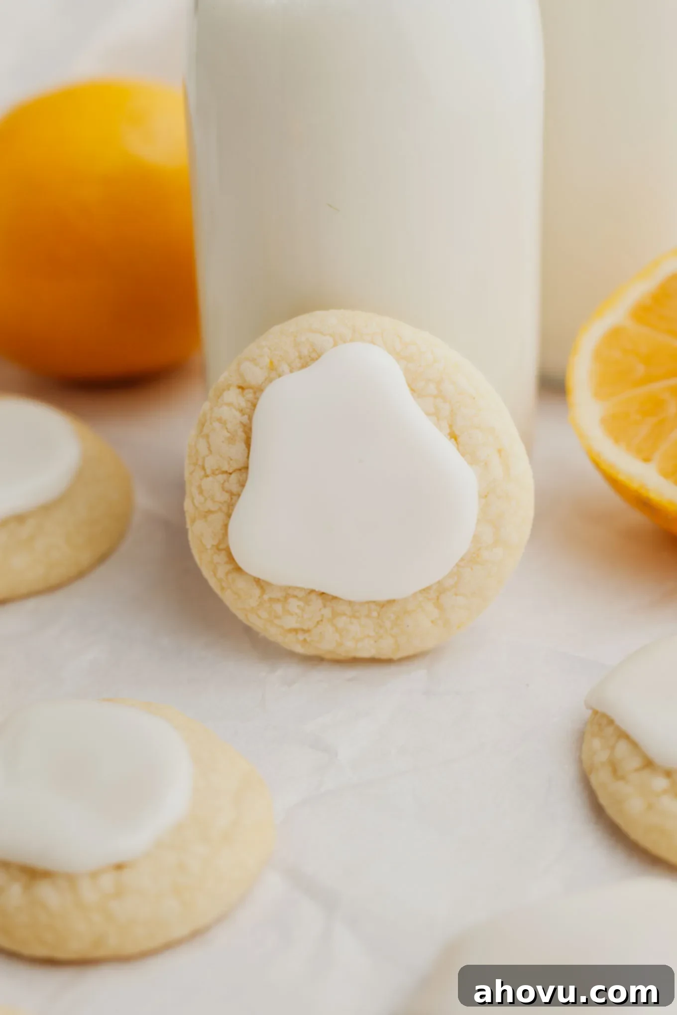 A perfectly baked lemon meltaway cookie, propped up against a small jug of milk, ready to be enjoyed.