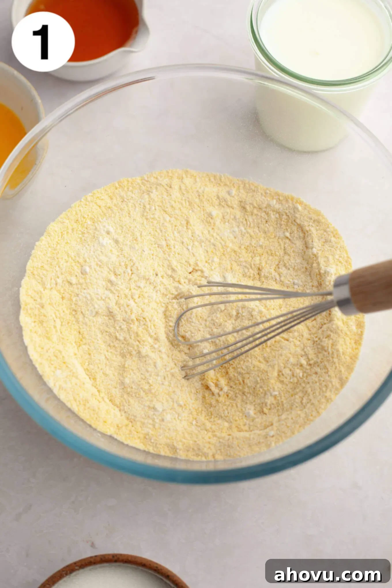An overhead view of the dry ingredients mixed together in a glass mixing bowl. 