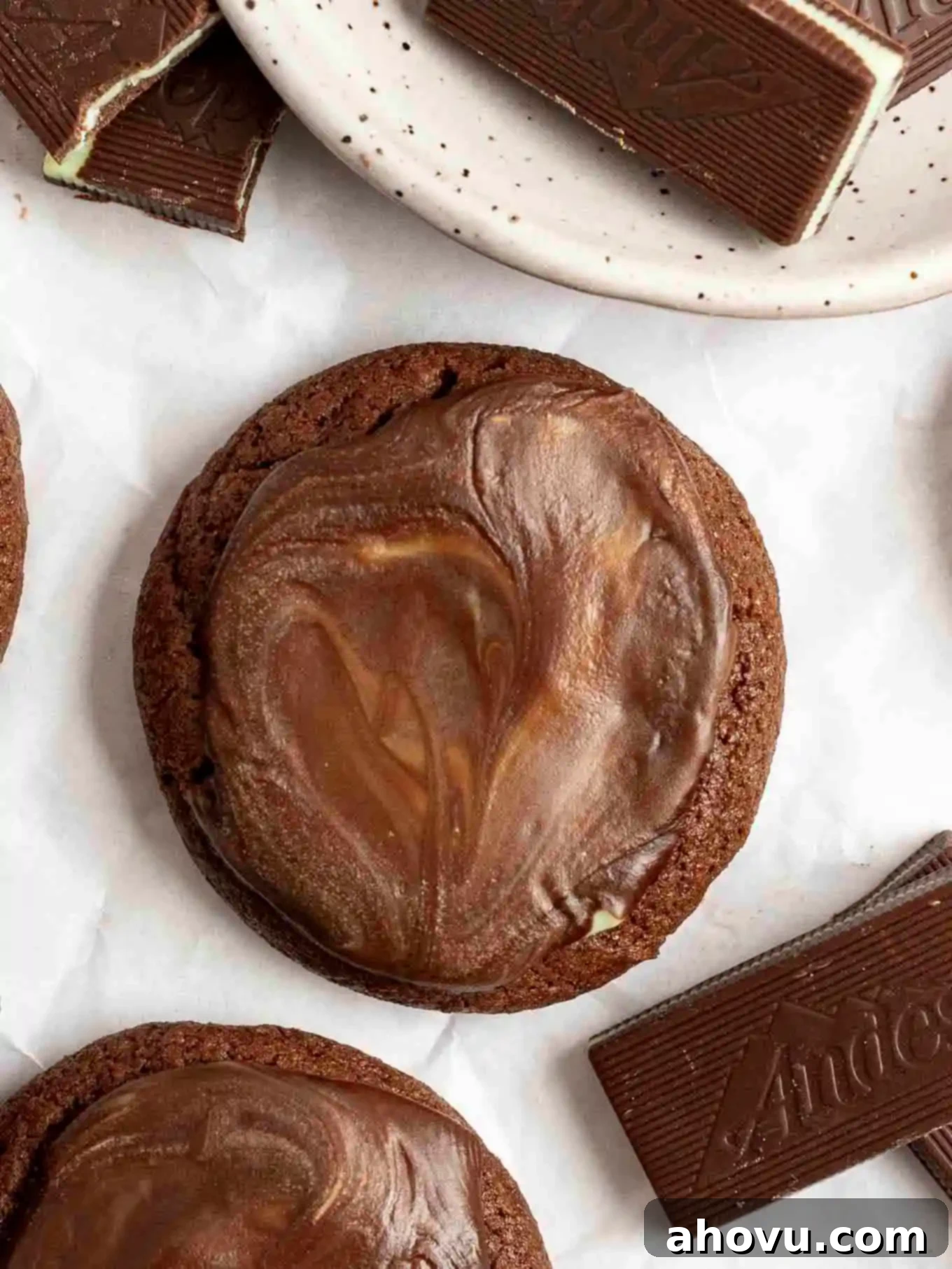 A close-up overhead view of a single Andes Mint cookie, showcasing its soft chocolate base and smooth, vibrant green mint topping.