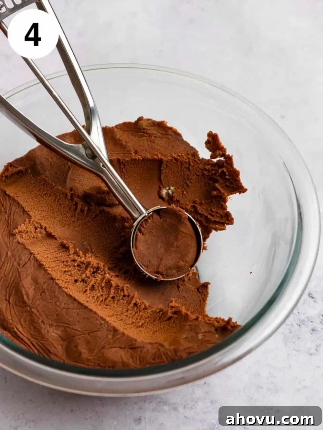 Chilled chocolate cookie dough in a glass mixing bowl, perfectly scooped into uniform balls with a cookie scoop, ready for baking.