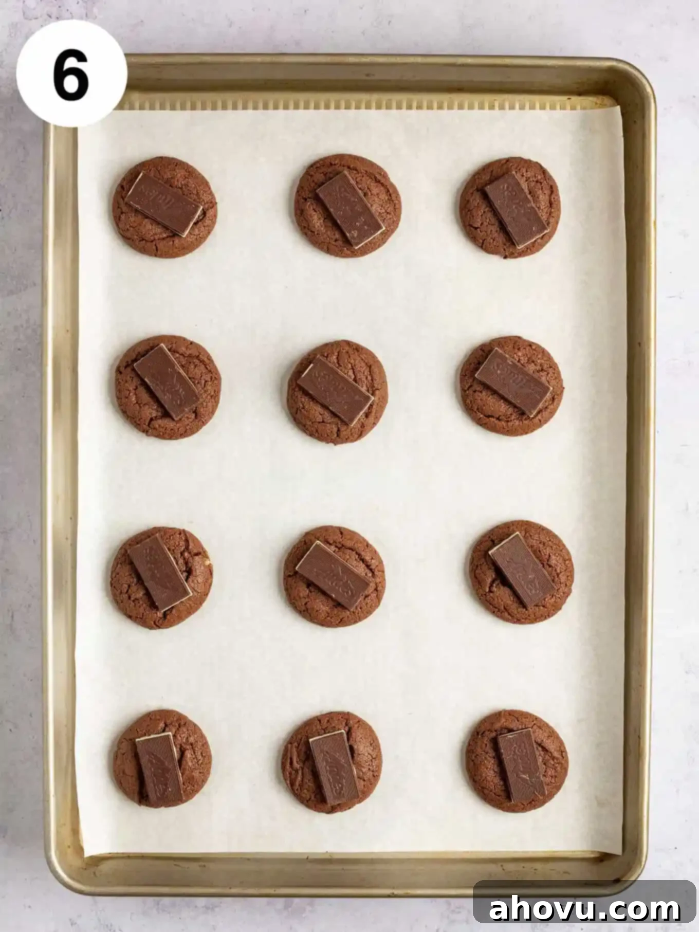 An overhead view of warm, baked chocolate cookies, each topped with a melting Andes mint, ready to be spread into a delicious icing.