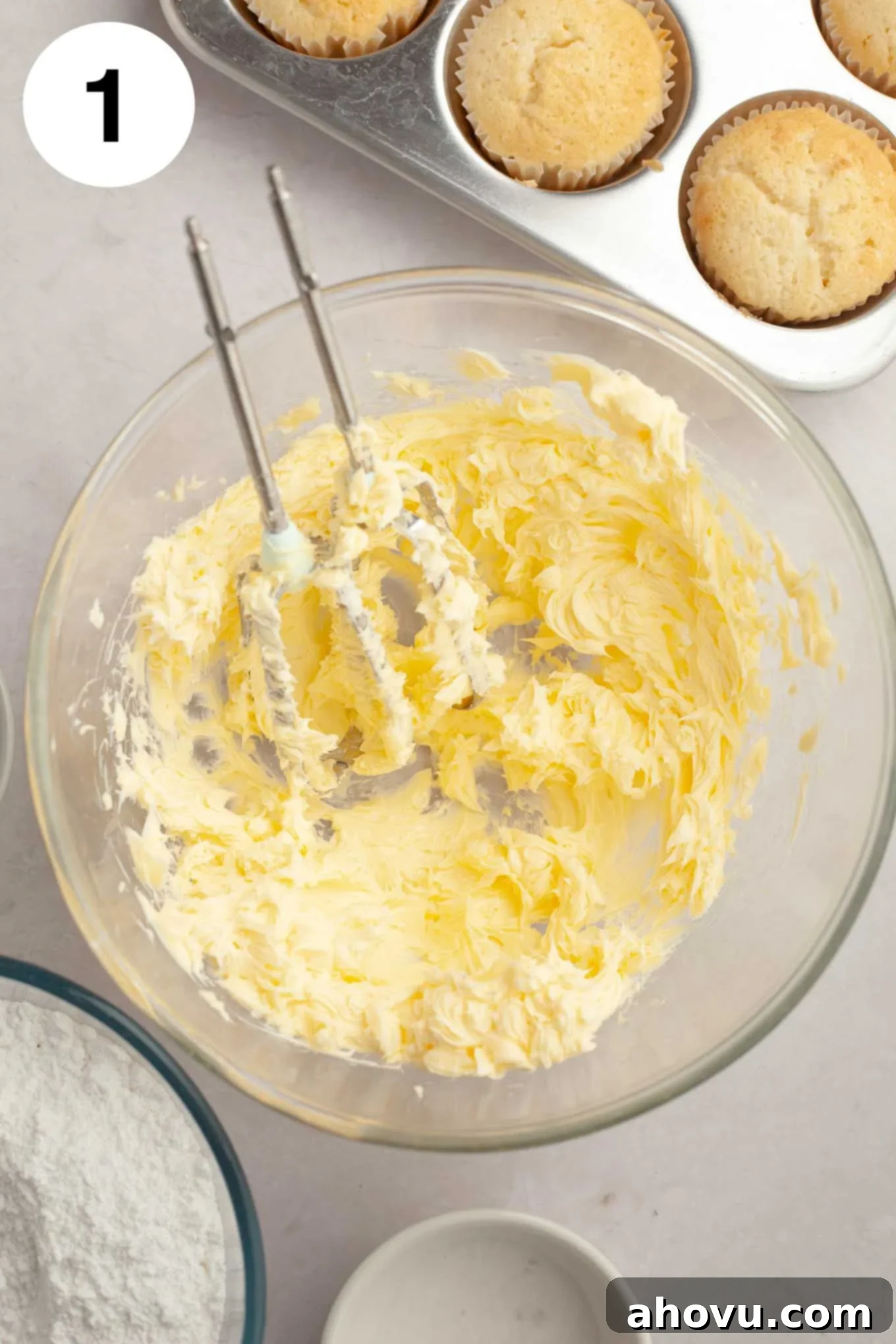A glass mixing bowl filled with unsalted butter that has been beaten until it is light, fluffy, and perfectly smooth.