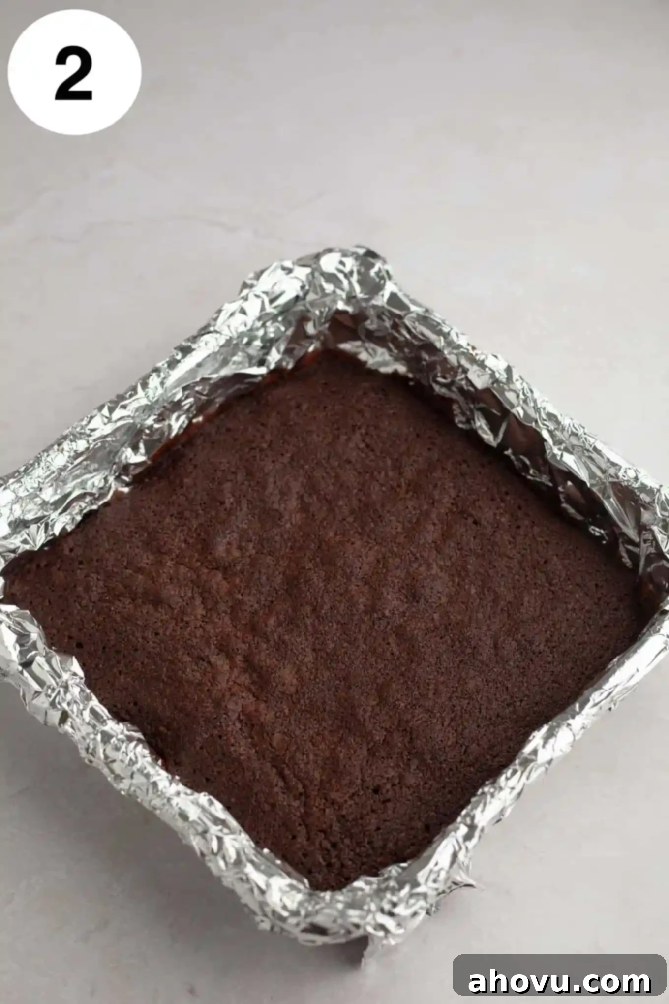 Buckeye Bliss Brownies 5 An overhead view of freshly baked, fudgy brownies cooling in a foil-lined square baking pan, their rich dark surface hinting at their deliciousness.