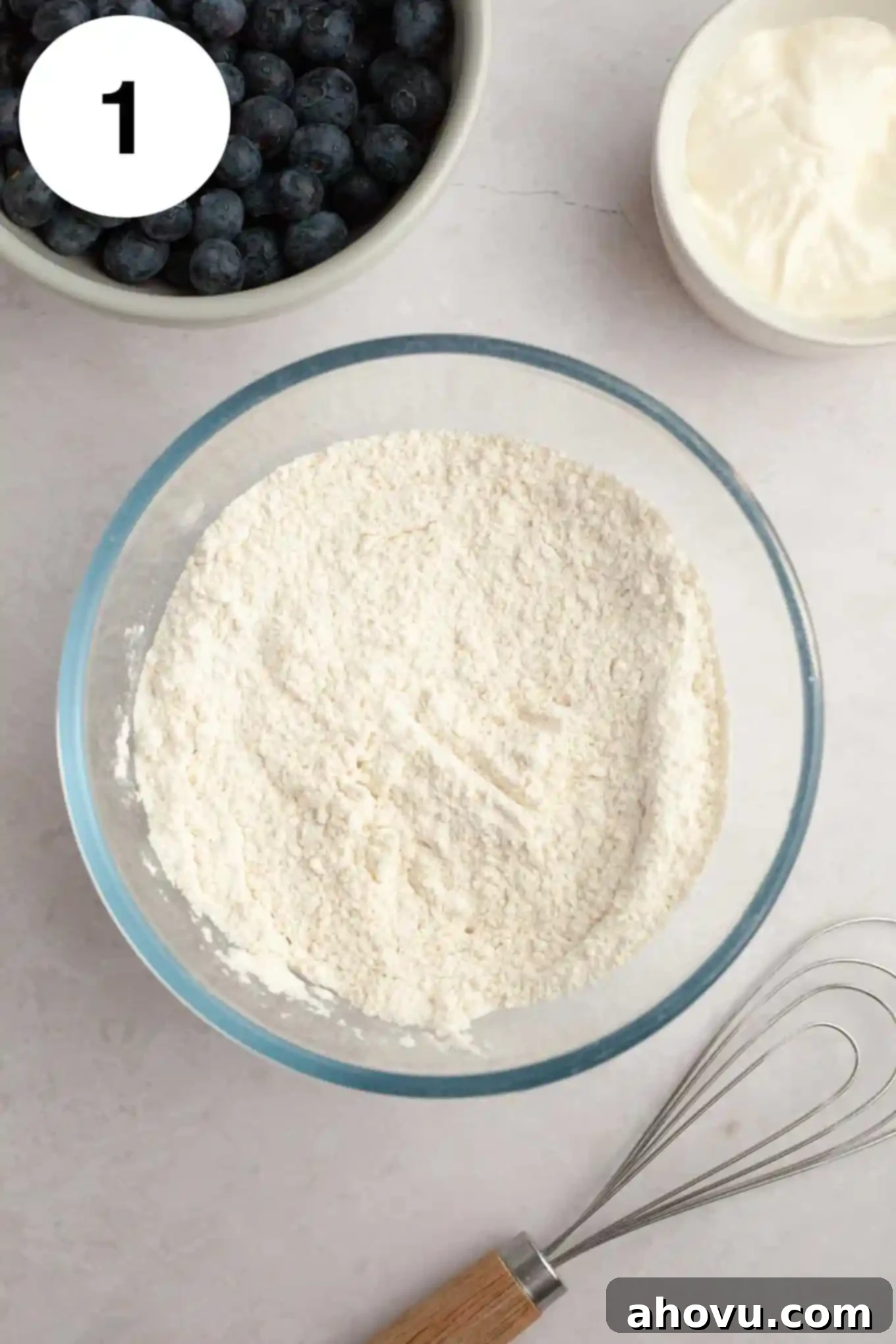 An overhead view of a flour mixture in a glass mixing bowl. 