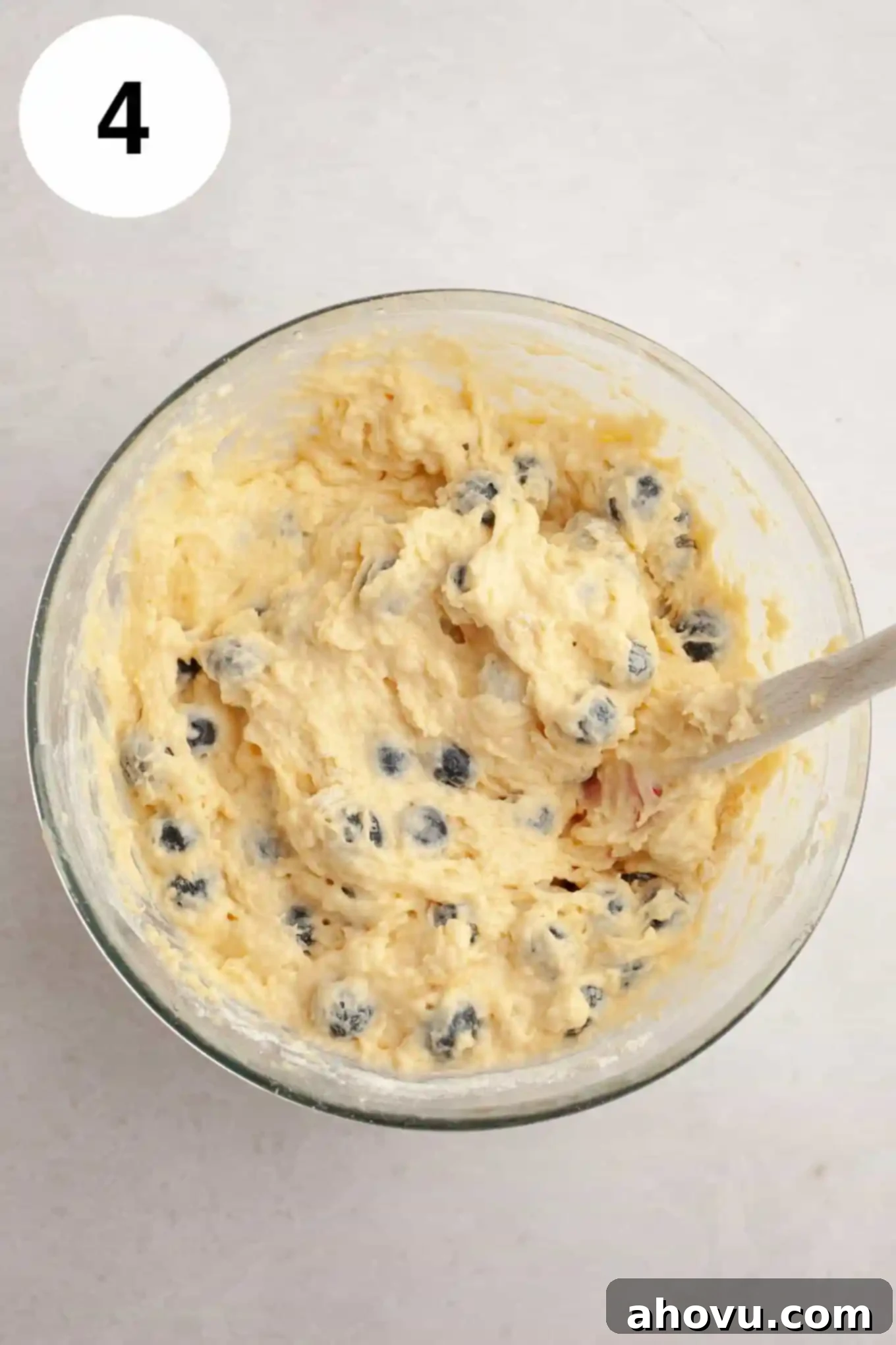 An overhead view of blueberry bread batter in a glass mixing bowl. 