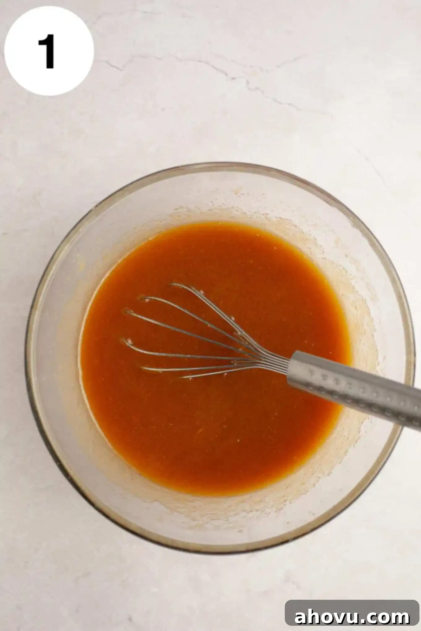 An overhead view of the wet ingredients, including melted butter, sugars, eggs, and vanilla, mixed together in a bowl.
