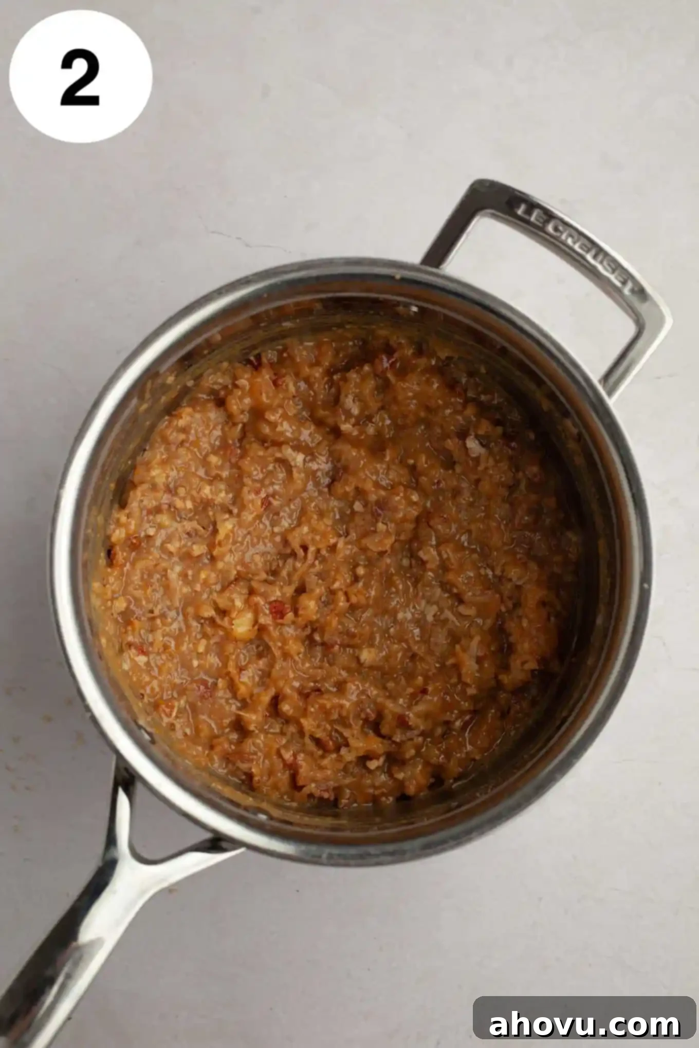 Decadent German Chocolate Cupcakes 6 A close-up, overhead view of the rich, caramel-colored coconut pecan frosting thickening in a saucepan, with visible pecans and shredded coconut stirred in.
