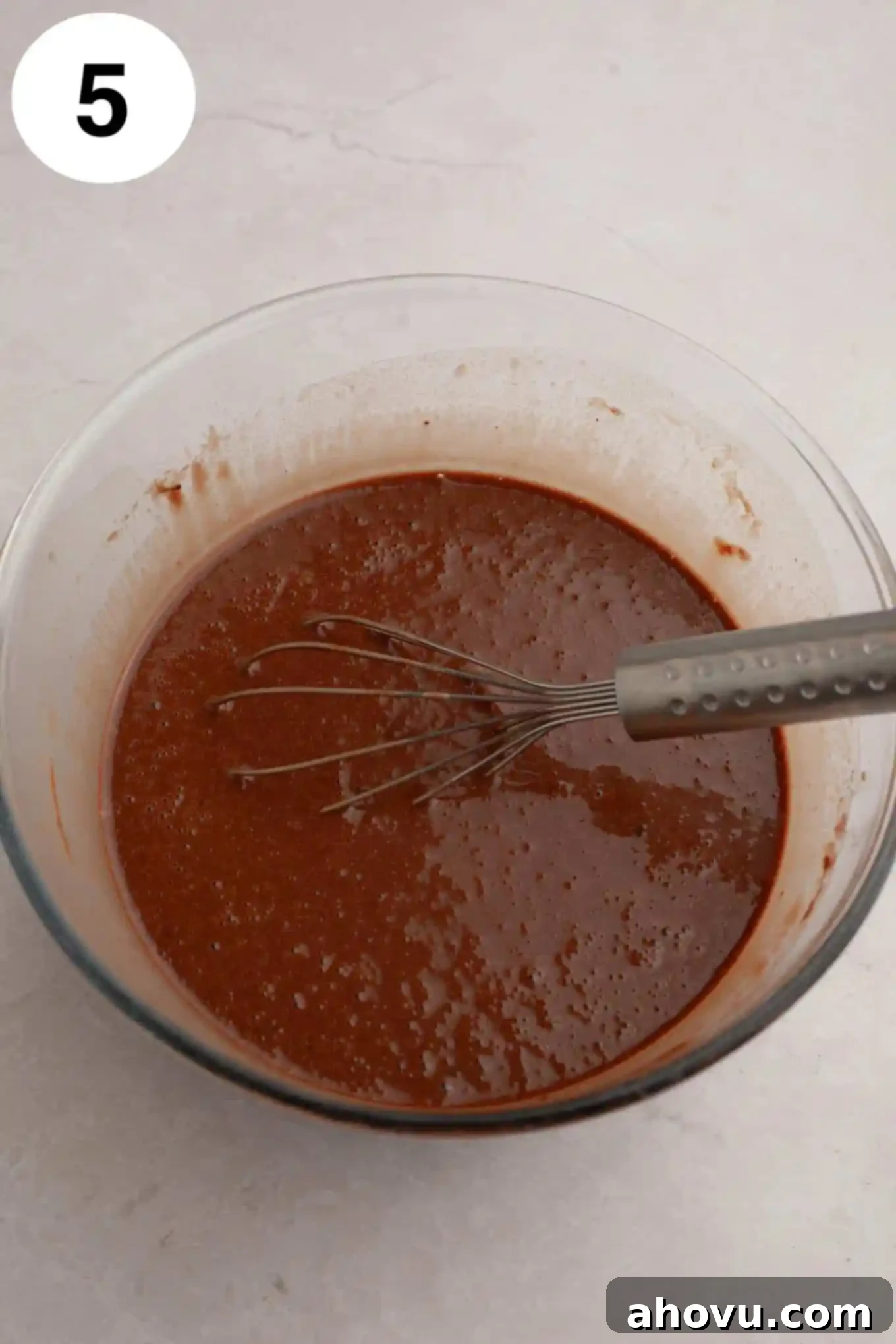 Decadent German Chocolate Cupcakes 9 An overhead view of chocolate cupcake batter, after all ingredients are combined, showing its smooth, pourable consistency in a glass mixing bowl with a whisk.