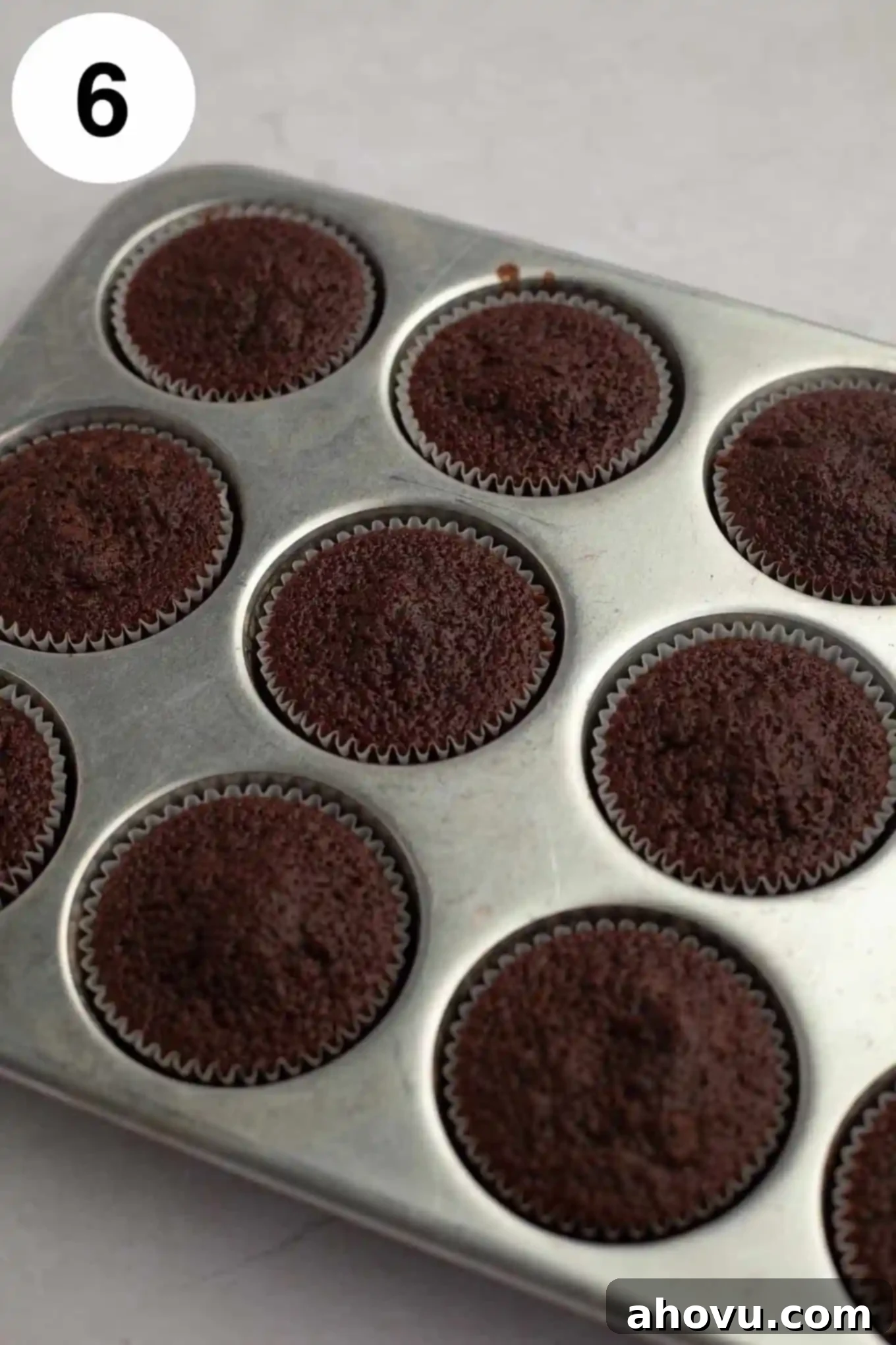 Decadent German Chocolate Cupcakes 10 Freshly baked chocolate cupcakes resting in a muffin pan, their tops perfectly domed and ready for cooling and frosting.