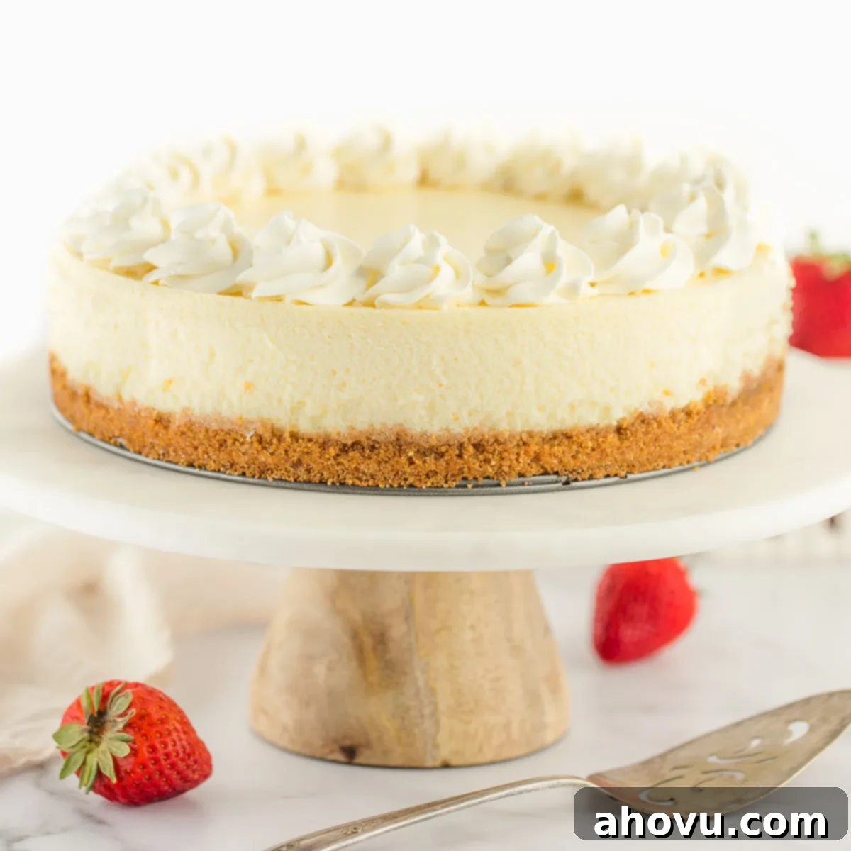 Your Guide to a Perfect Cheesecake Water Bath 12 A cheesecake topped with whipped cream sitting on a marble cake stand.