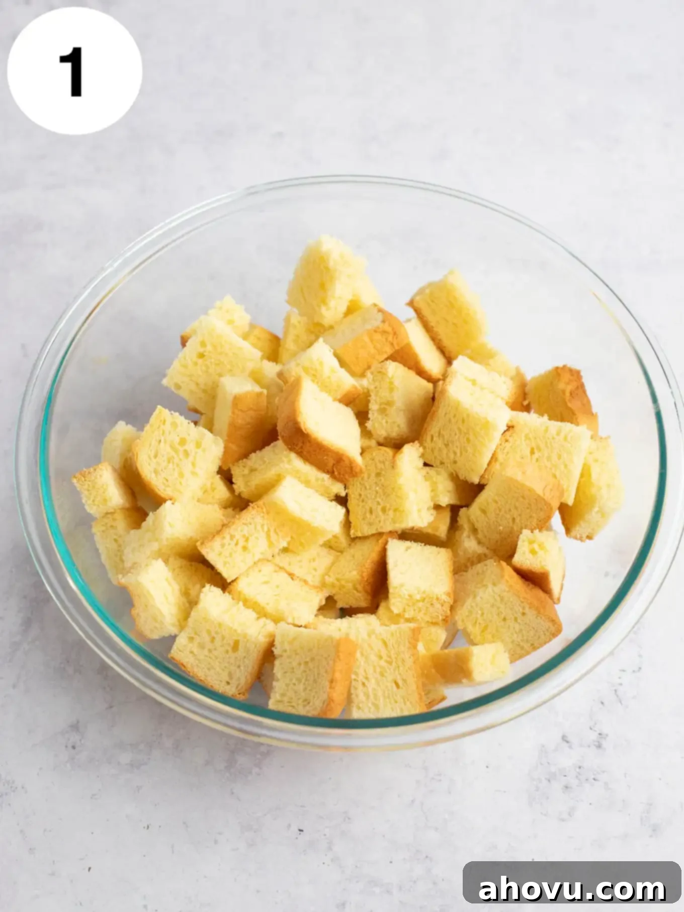 Cubed bread in a large glass mixing bowl.