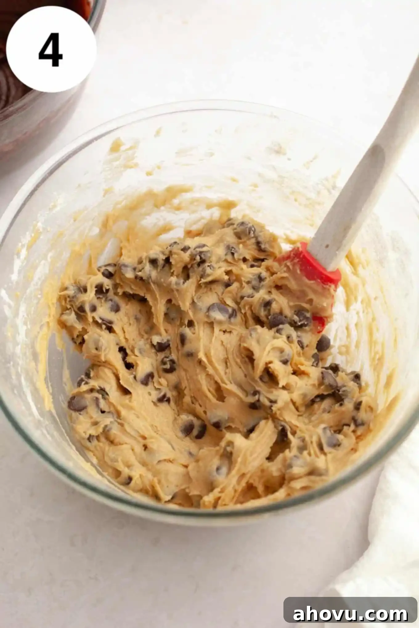 Gems of the Current 7 An overhead view of chocolate chip cookie dough in a glass mixing bowl, with a whisk.