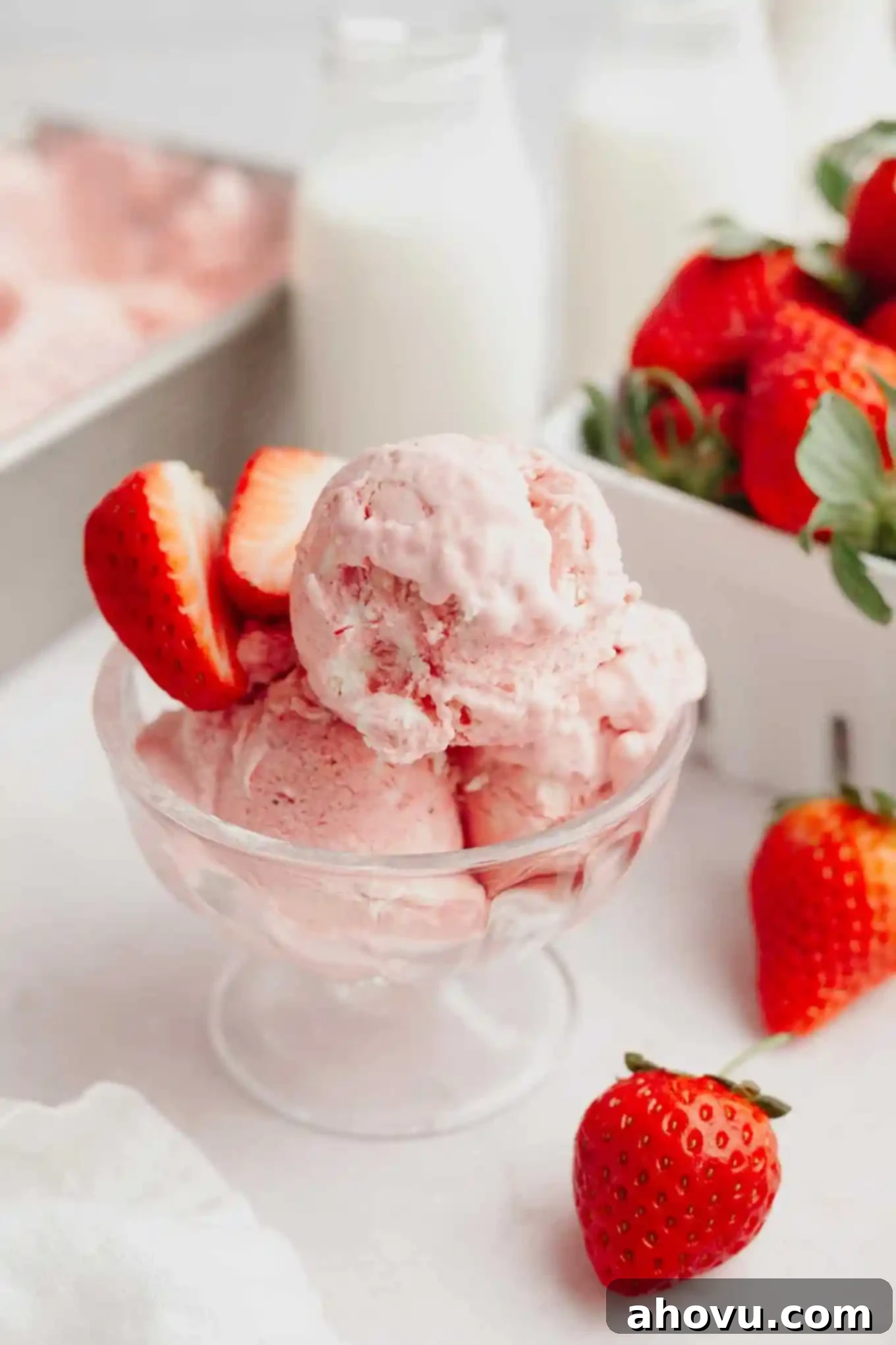 Three generous scoops of vibrant no-churn strawberry ice cream nestled in an elegant glass ice cream dish, ready to be enjoyed.