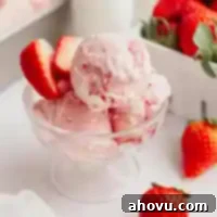 A small glass bowl filled with perfectly scooped homemade strawberry ice cream, garnished with fresh whole strawberries.