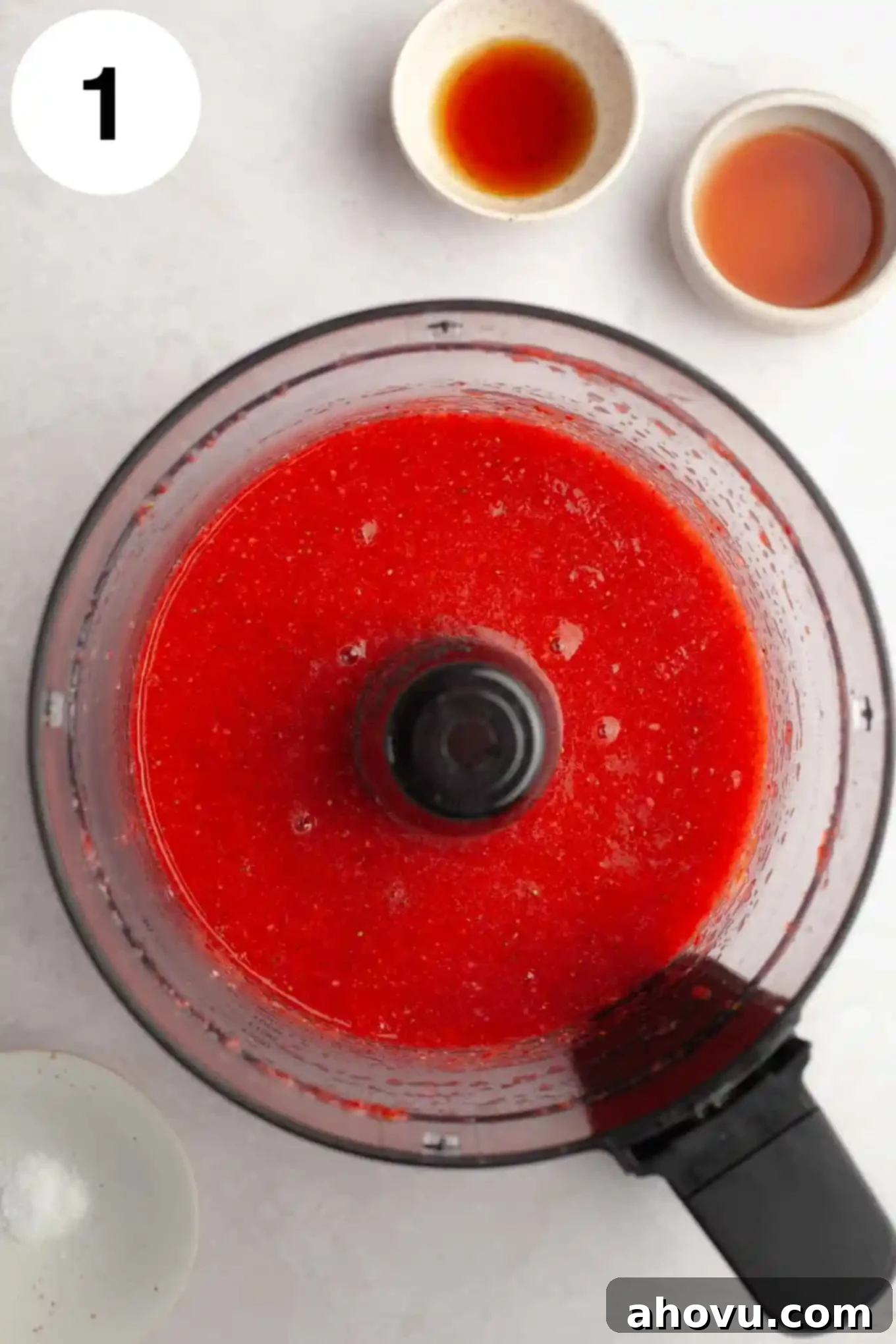 An overhead shot showing vibrant fresh strawberry puree being prepared in a food processor, capturing its smooth, liquid texture.