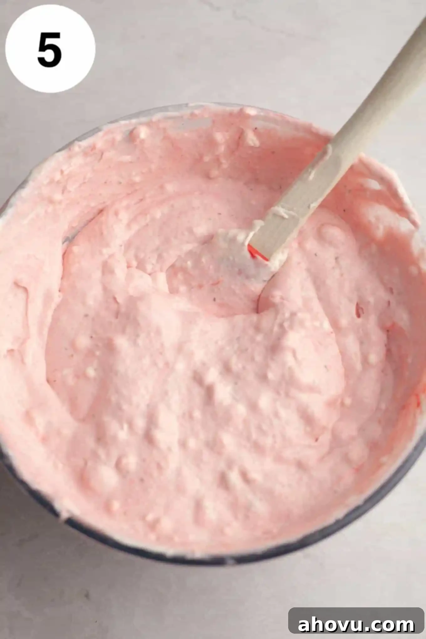 An overhead shot of the beautifully pink strawberry ice cream mixture gently combined in a large mixing bowl, showcasing its smooth and creamy texture before freezing.
