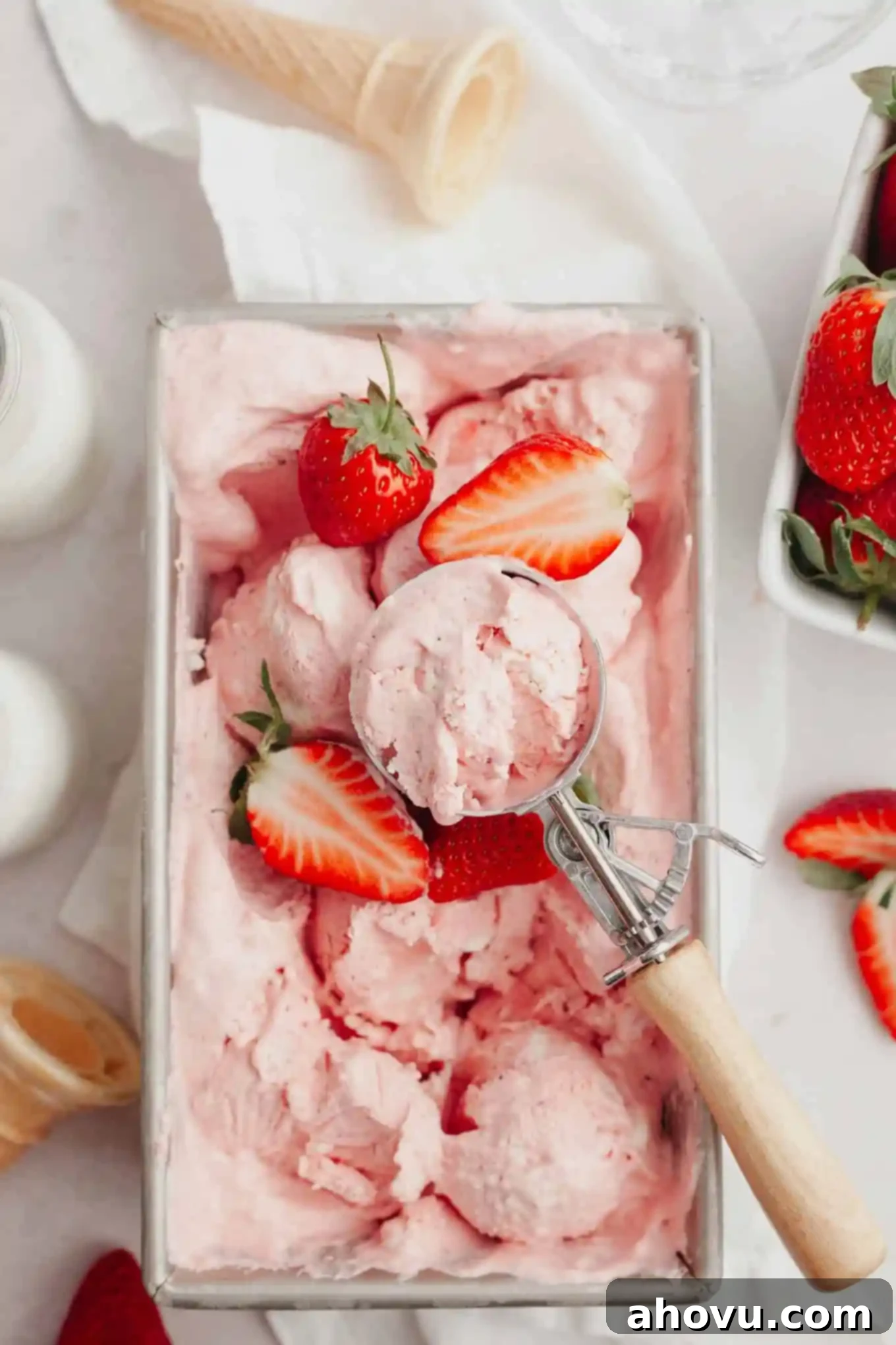 An overhead shot of delectable strawberry ice cream in a metal loaf pan, beautifully garnished with a few fresh berries, indicating it's ready to serve.