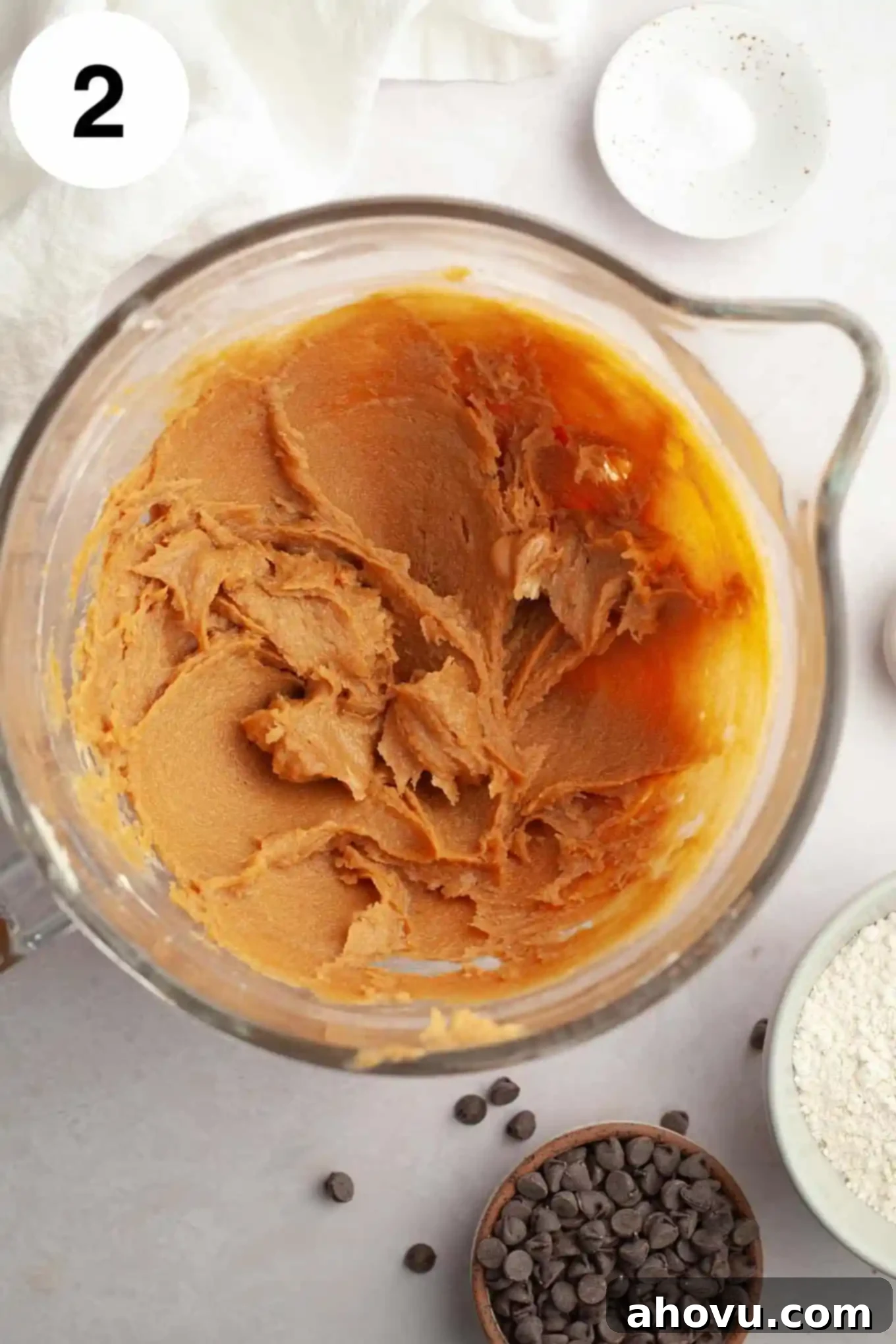 Irresistible Peanut Butter Chocolate Chip Cookies 5 An overhead view of butter, sugar, and peanut butter creamed together in a glass mixing bowl.