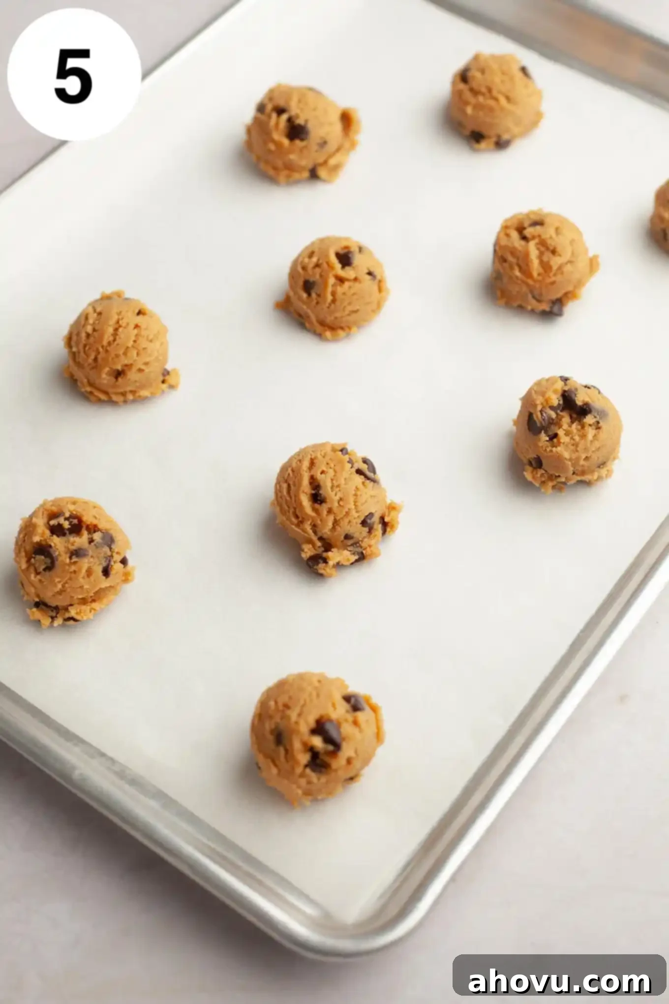Irresistible Peanut Butter Chocolate Chip Cookies 8 Balls of peanut butter chocolate chip cookie dough on a parchment-lined baking sheet.