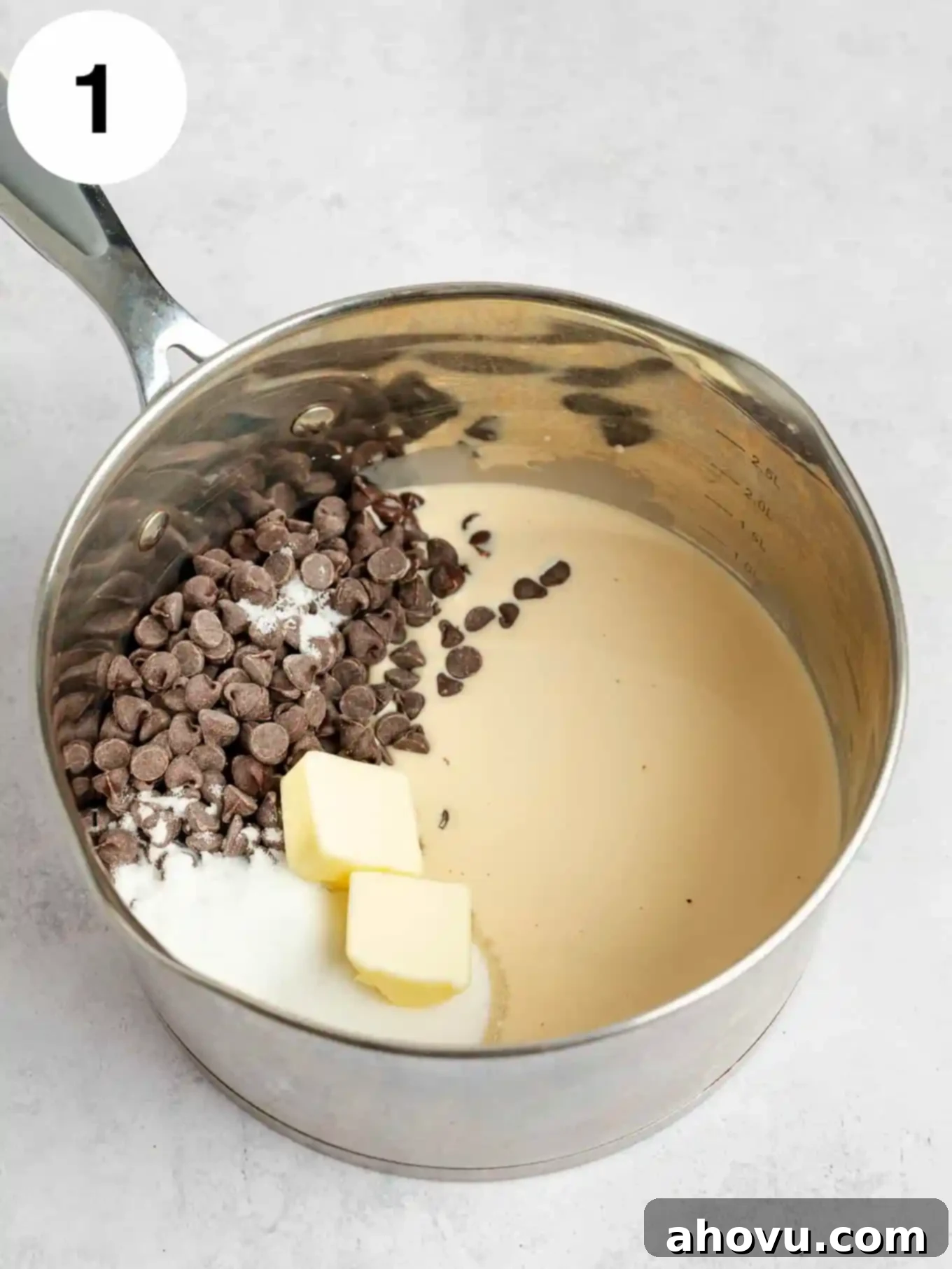 A metal saucepan filled with a mixture of evaporated milk, granulated sugar, unsalted butter, a pinch of salt, and semi-sweet chocolate chips, ready to be heated.