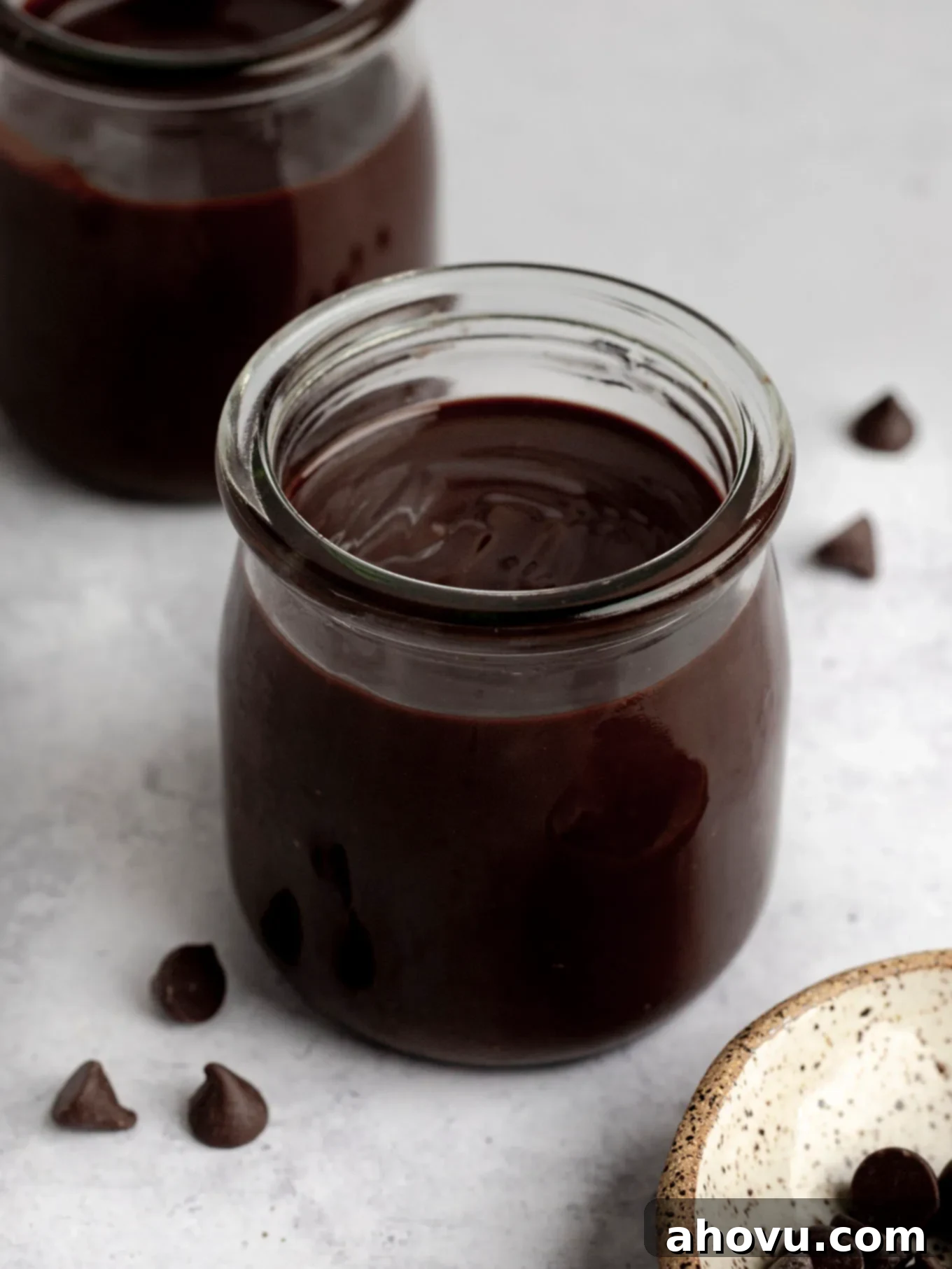 A rustic glass jar filled with the rich, dark, and glossy homemade hot fudge sauce, ready for storage or serving.
