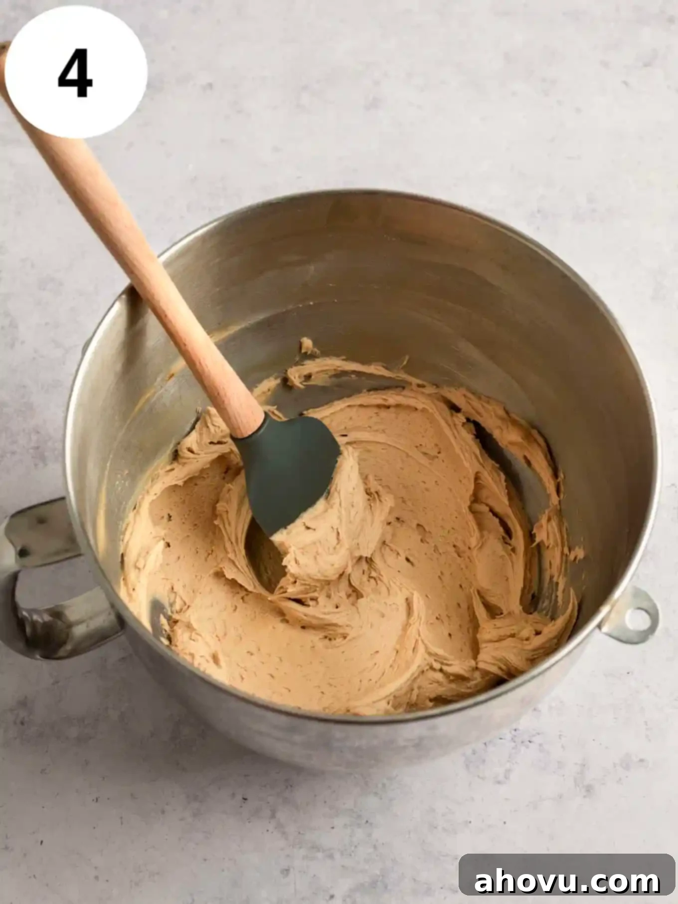 Creamy coffee frosting in the bowl of a stand mixer, with a rubber spatula. 