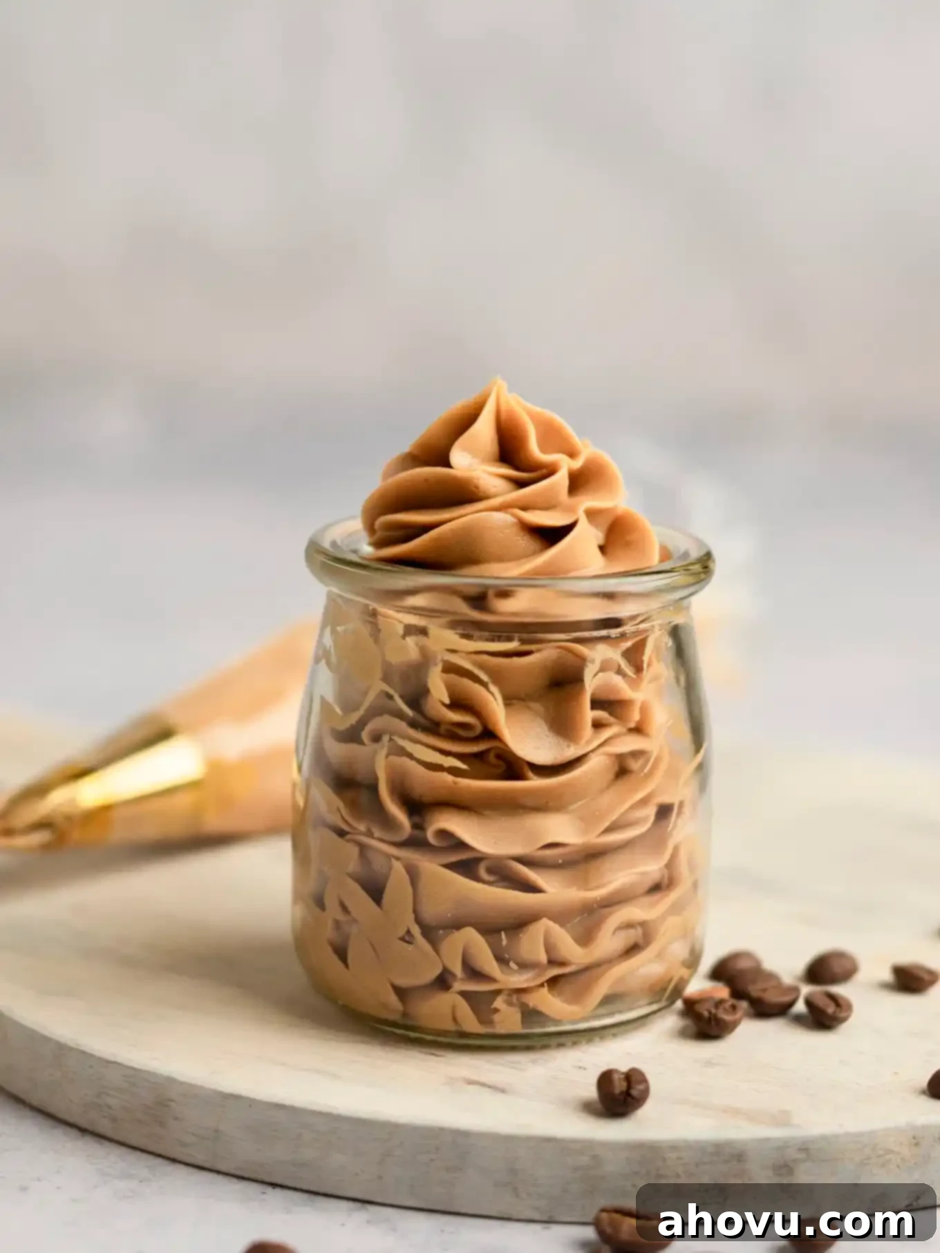 Coffee buttercream frosting piped into a clear glass jar. 