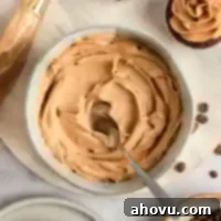 A bowl filled with coffee frosting and a spoon.