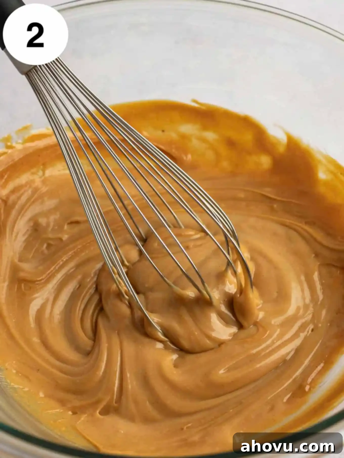 Velvet Peanut Butter Freeze 5 A smooth mixture of peanut butter, sweetened condensed milk, and vanilla extract in a glass mixing bowl, with a whisk resting inside.