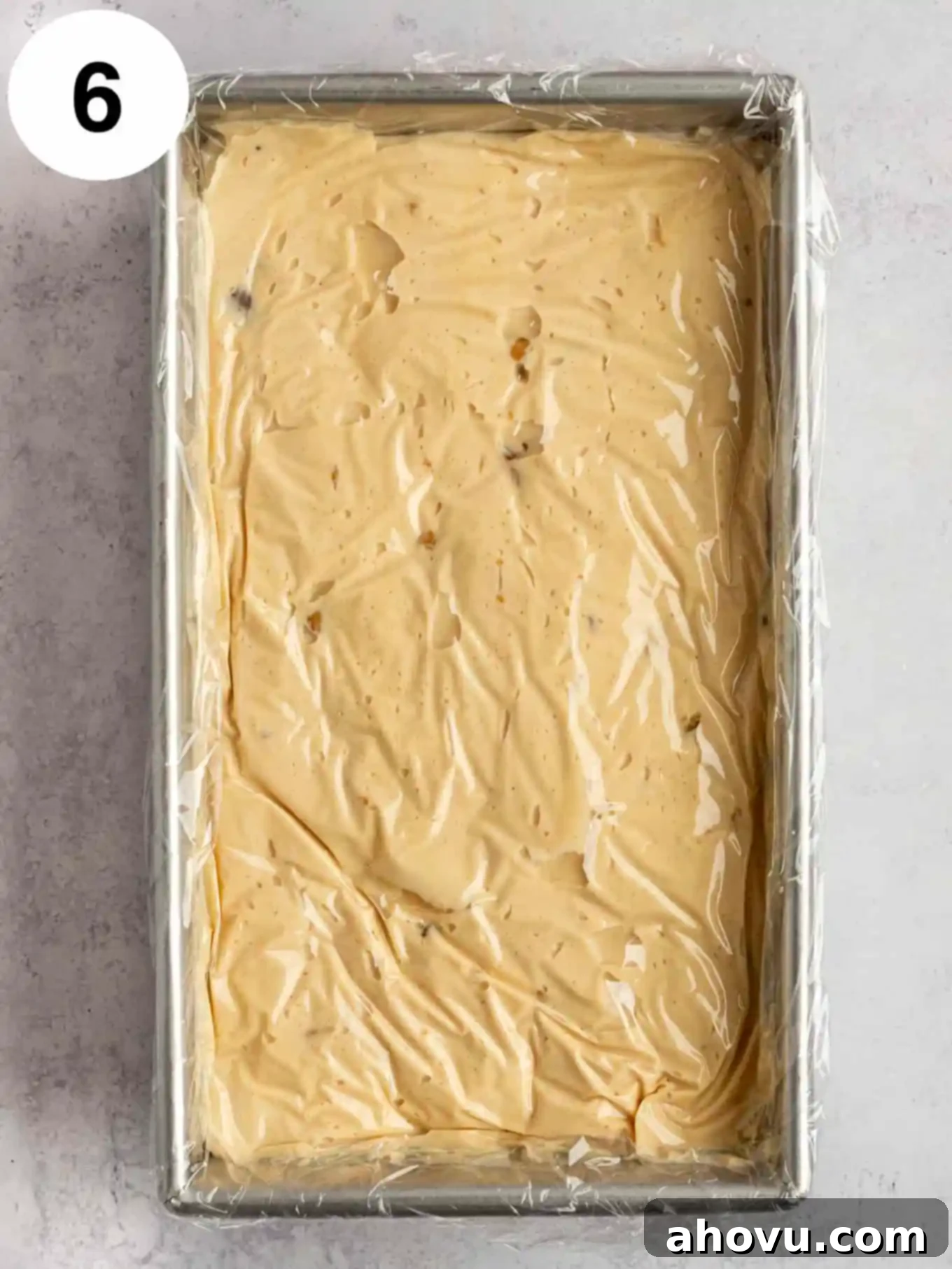 Velvet Peanut Butter Freeze 9 An overhead view of the peanut butter ice cream mixture pressed into a loaf pan, covered with plastic wrap directly touching the surface, ready for freezing.