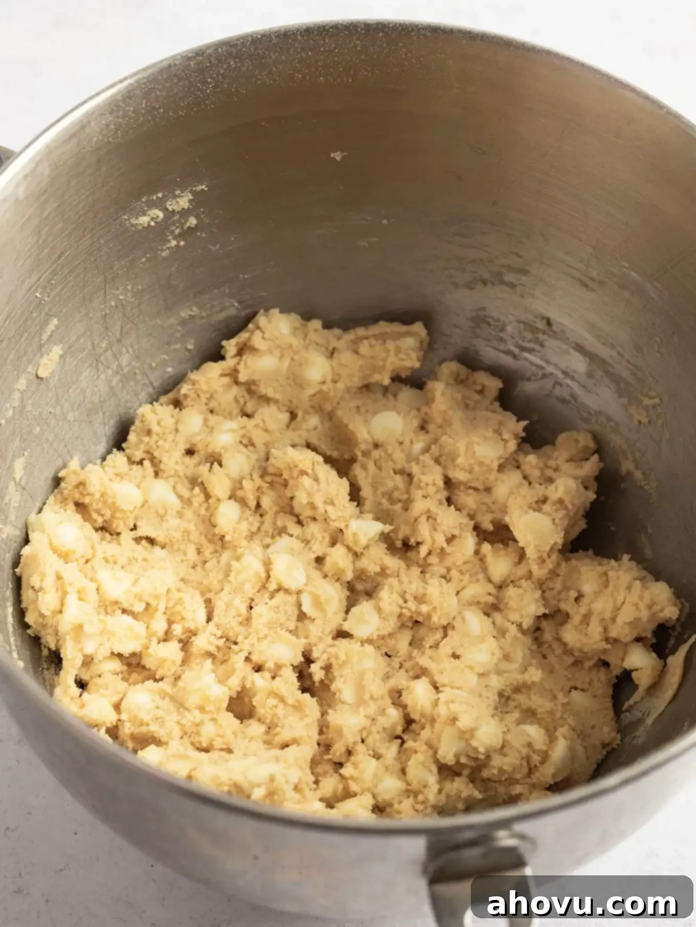 White chocolate chip cookie dough fully mixed in the bowl of a stand mixer, showcasing the incorporation of all ingredients and the distinct white chocolate chips throughout.