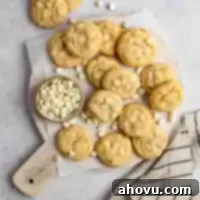 An overhead view of delicious homemade white chocolate chip cookies artfully arranged on a rustic wooden board, ready to be enjoyed.