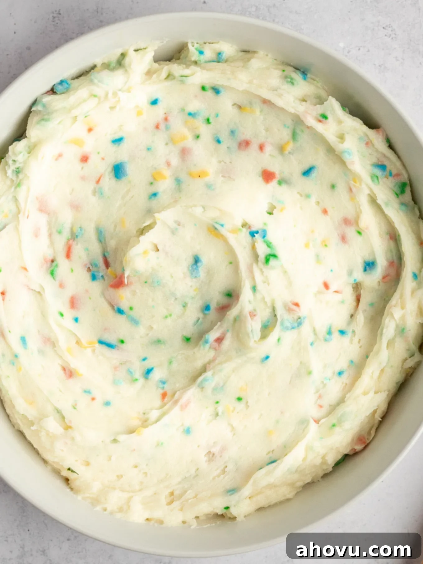 Joyful Confetti Frosting 11 A close-up, overhead view of homemade frosting with rainbow chips.