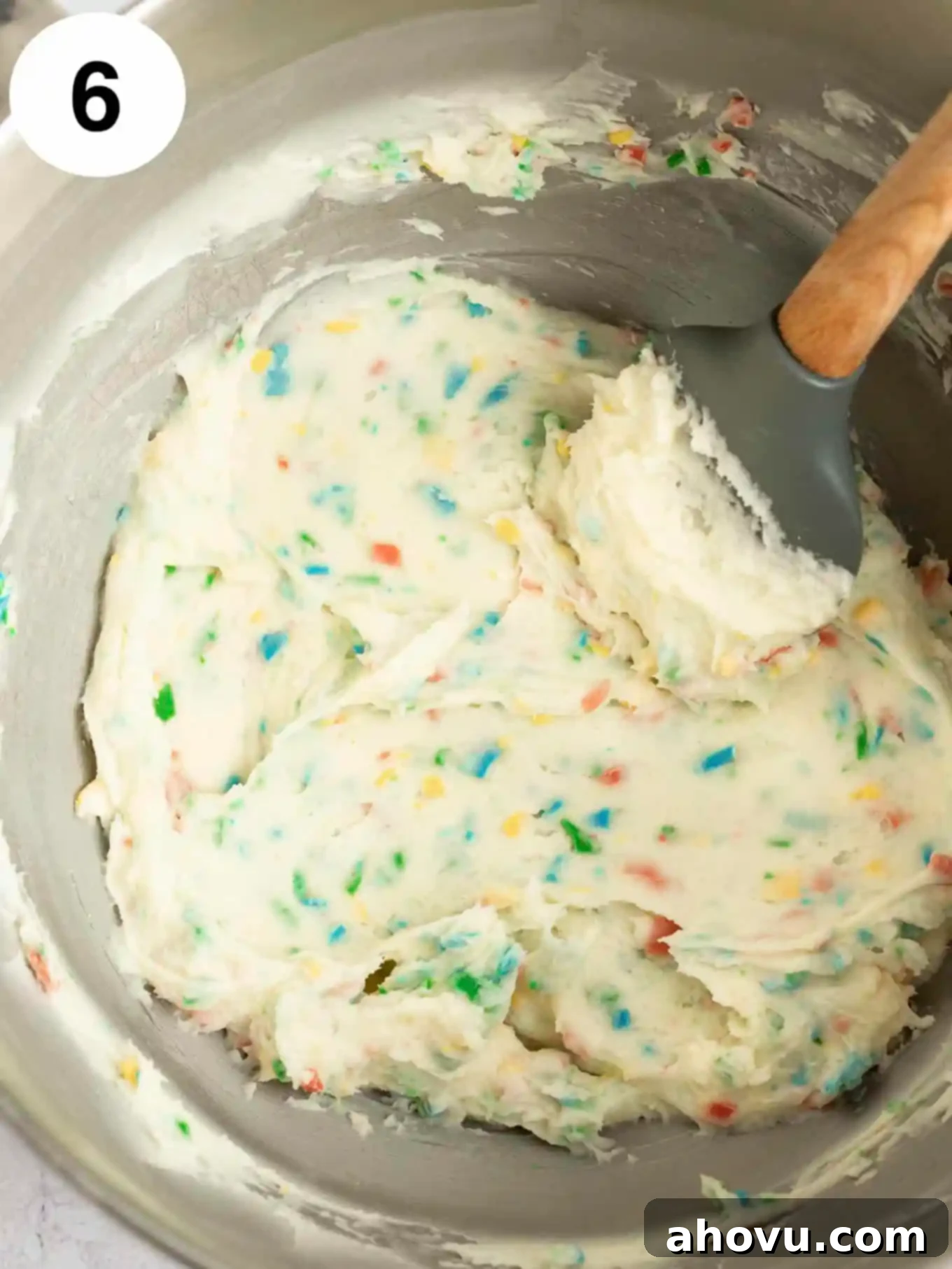 Joyful Confetti Frosting 9 An overhead view of rainbow chip frosting in a mixing bowl, with a rubber spatula.