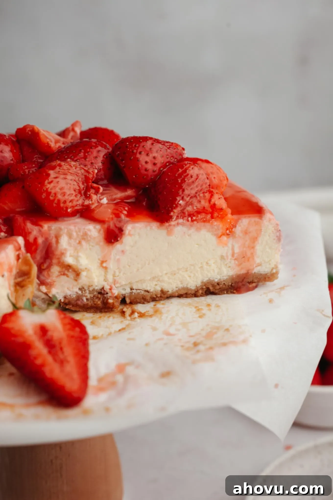 A beautiful side view of a perfectly sliced strawberry cheesecake presented on an elegant cake stand.