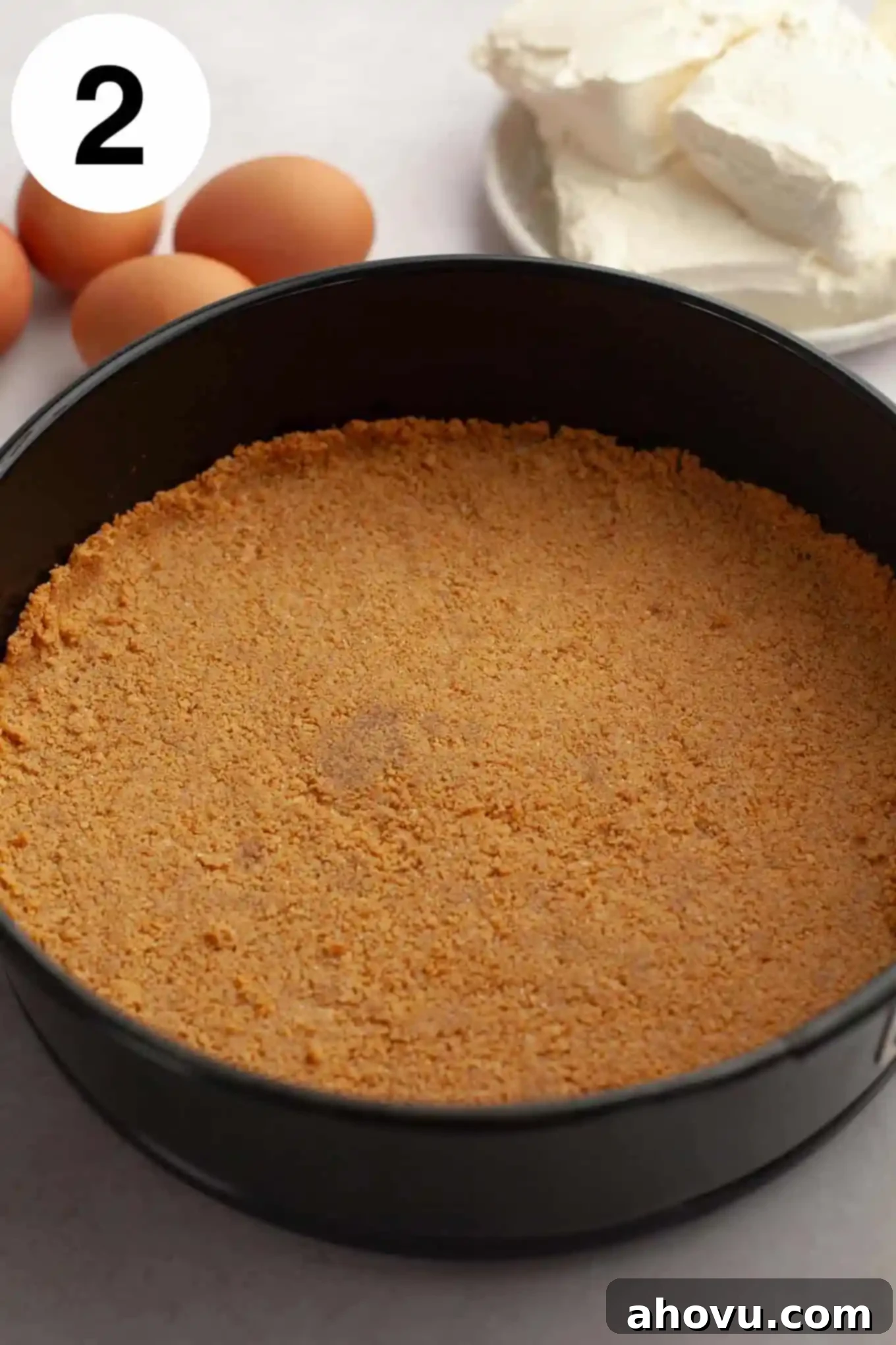 An overhead perspective of a golden-brown graham cracker crust, neatly pressed into a springform pan, ready for the cheesecake filling.