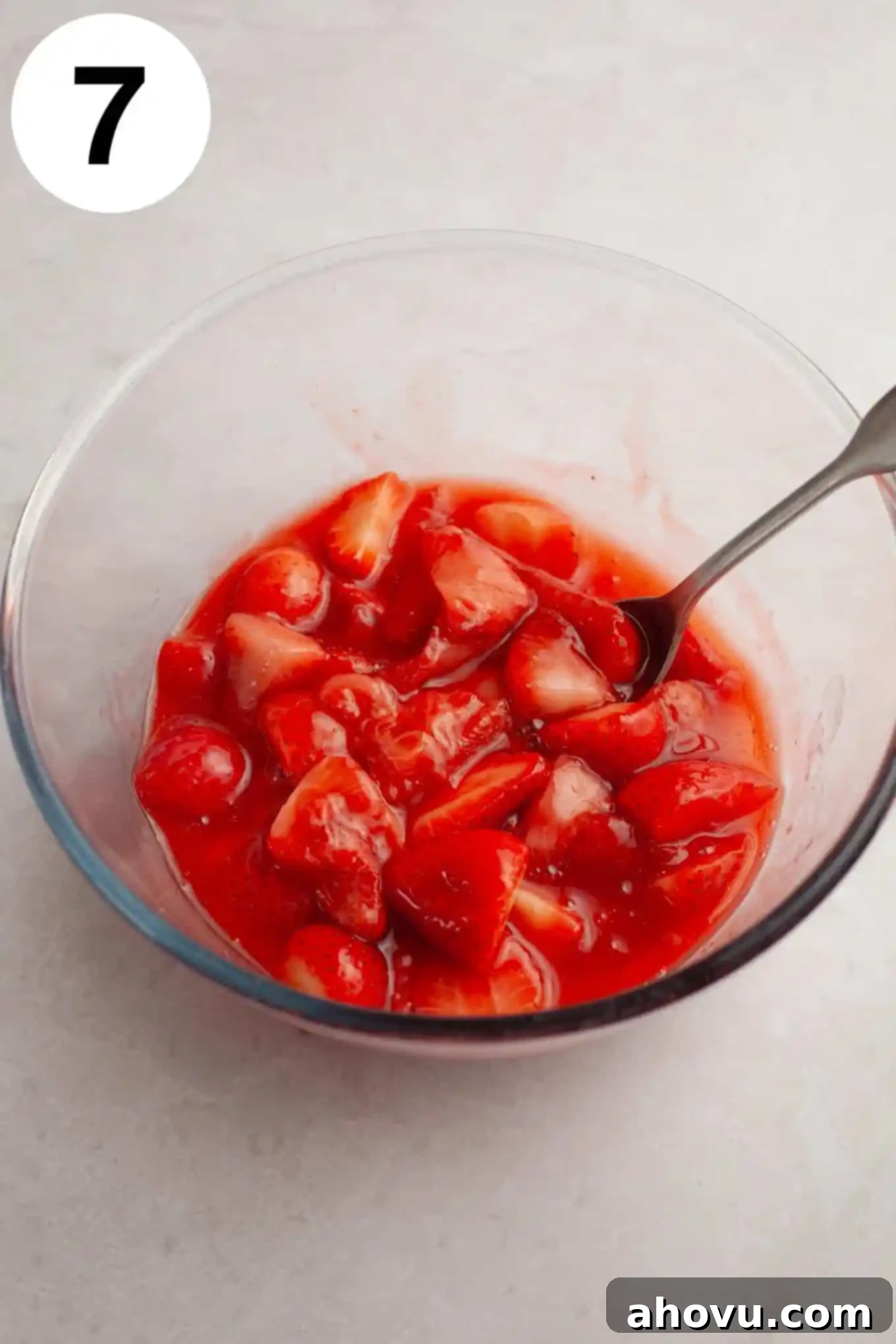 An overhead view of luscious strawberry topping in a glass mixing bowl, glistening and ready to be used.